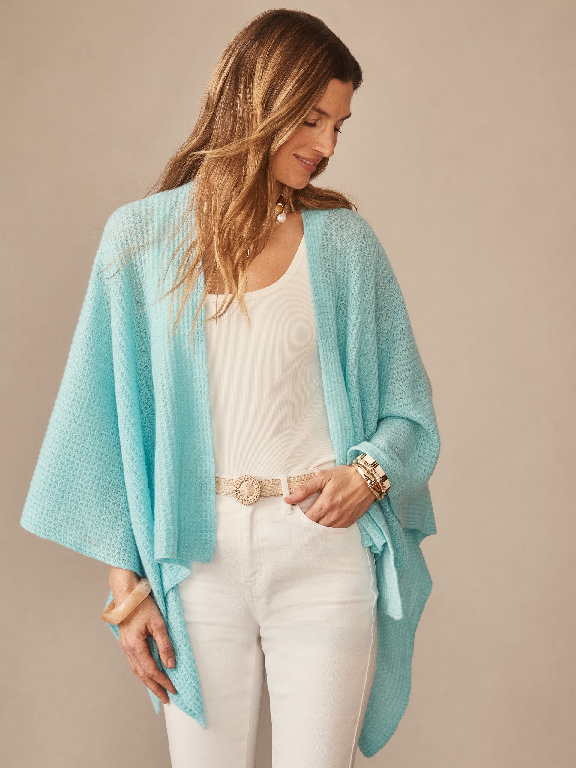 Woman wearing a seafoam blue Julianne Cashmere Wrap over a white top and pants, styled with gold bracelets and a woven belt, showcasing J.McLaughlin’s effortlessly stylish, enduring designs.