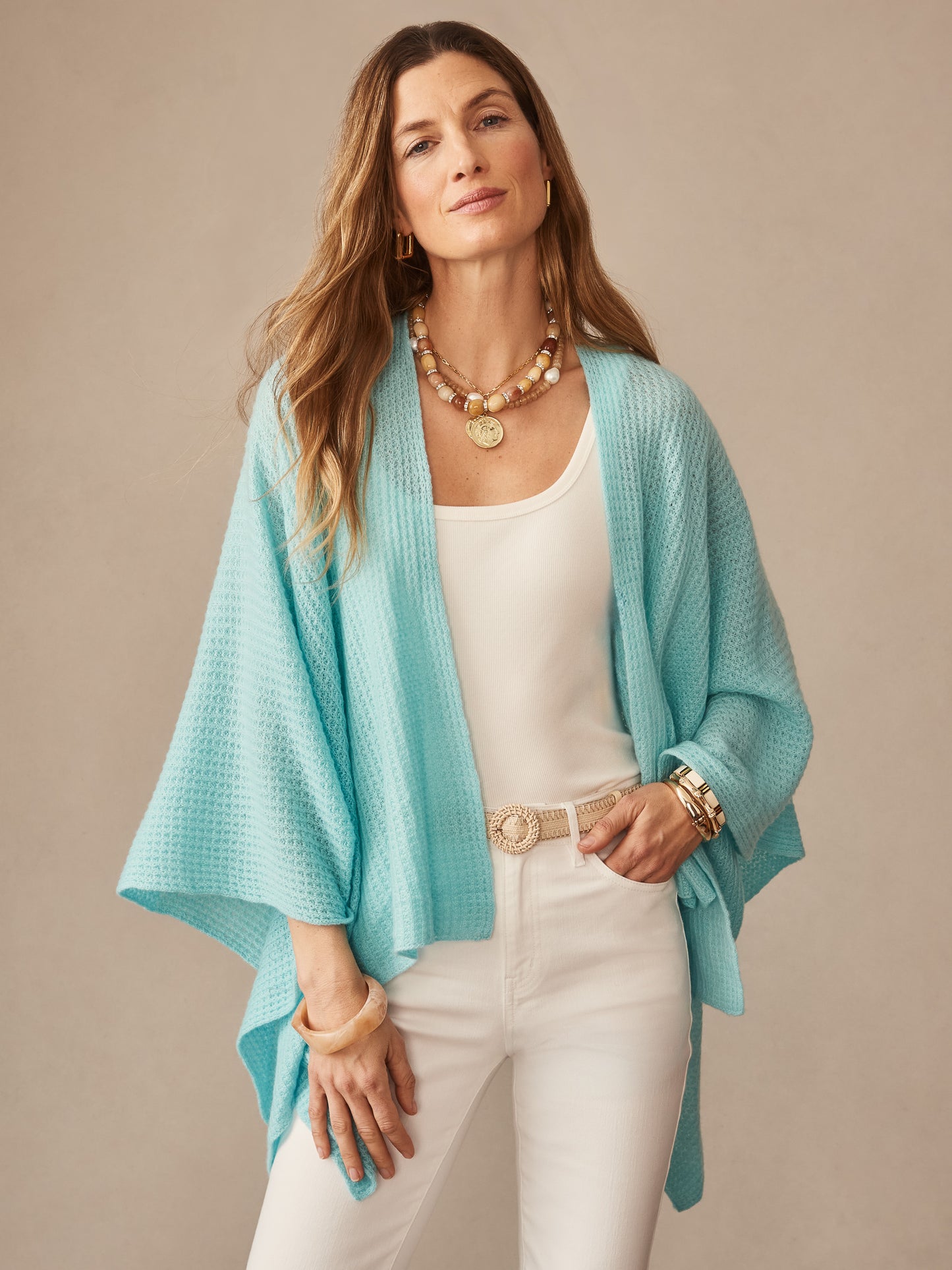 Woman wearing a seafoam cashmere wrap called Julianne Cashmere Wrap by J.McLaughlin over a white tank and pants, accessorized with gold jewelry, embodying effortlessly stylish, enduring designs and innovative fabrics.