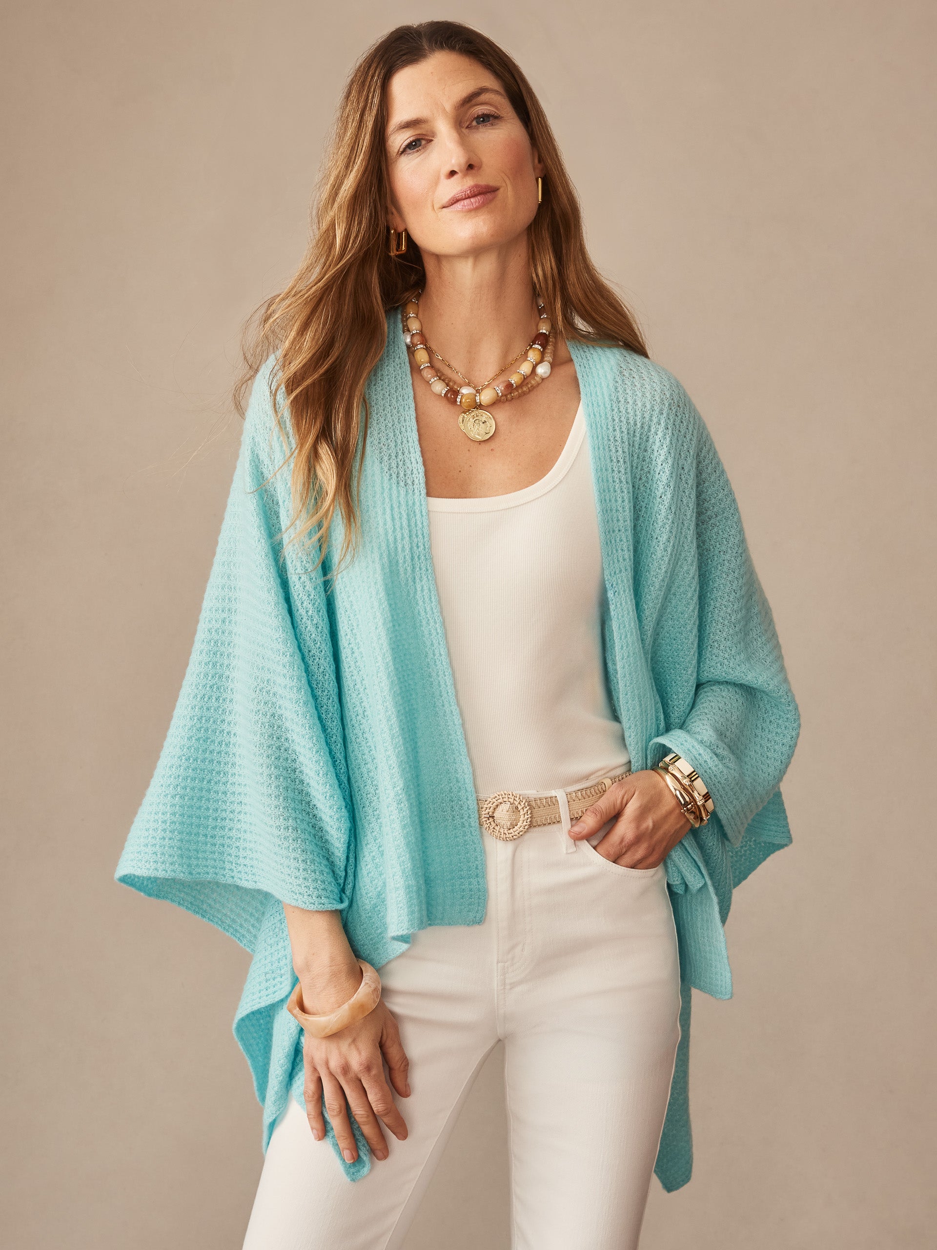 Woman wearing a seafoam cashmere wrap called Julianne Cashmere Wrap by J.McLaughlin over a white tank and pants, accessorized with gold jewelry, embodying effortlessly stylish, enduring designs and innovative fabrics.