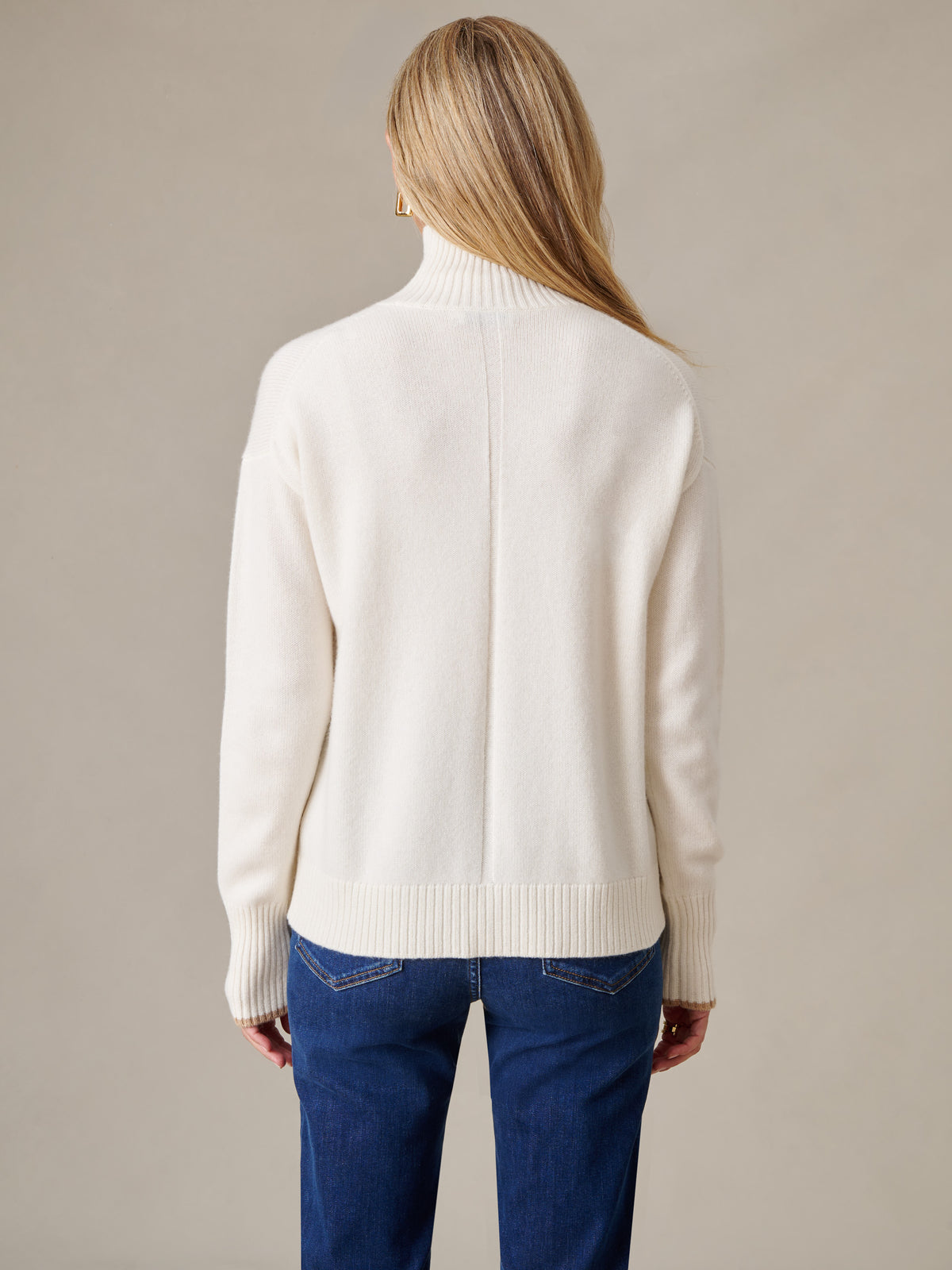 J.McLaughlin Dina Cashmere Turtleneck in ivory with ribbed cuffs and hem styled with blue jeans viewed from the back