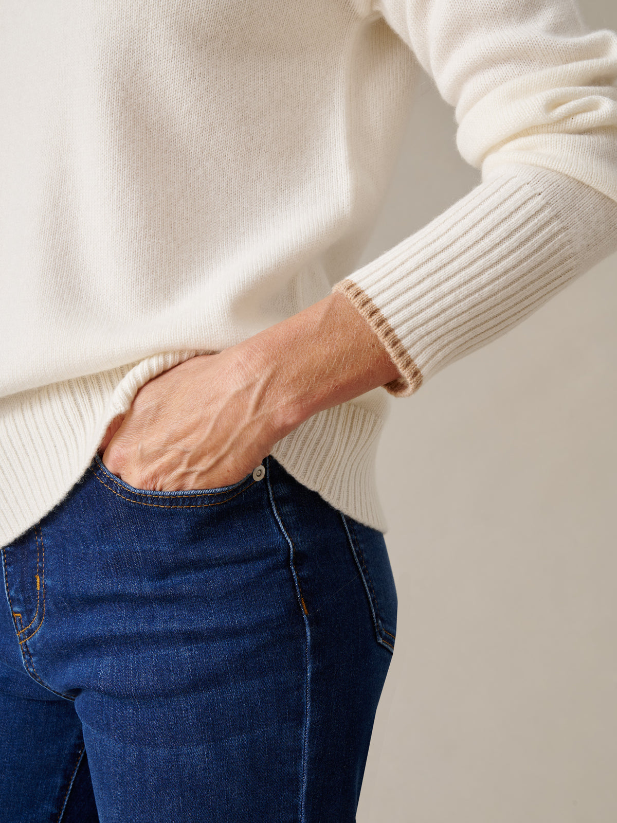 J.McLaughlin Dina Cashmere Turtleneck in soft cream with ribbed cuffs styled with dark blue jeans and a hand in the pocket