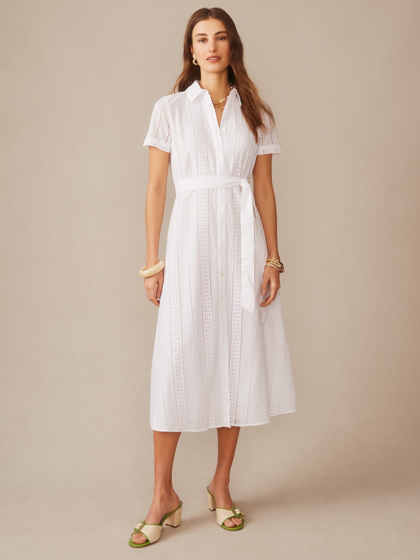 Woman wearing a white Kalinda Dress in Eyelet by J.McLaughlin, featuring a belted waist and button-down front, showcasing effortlessly stylish and enduring designs.