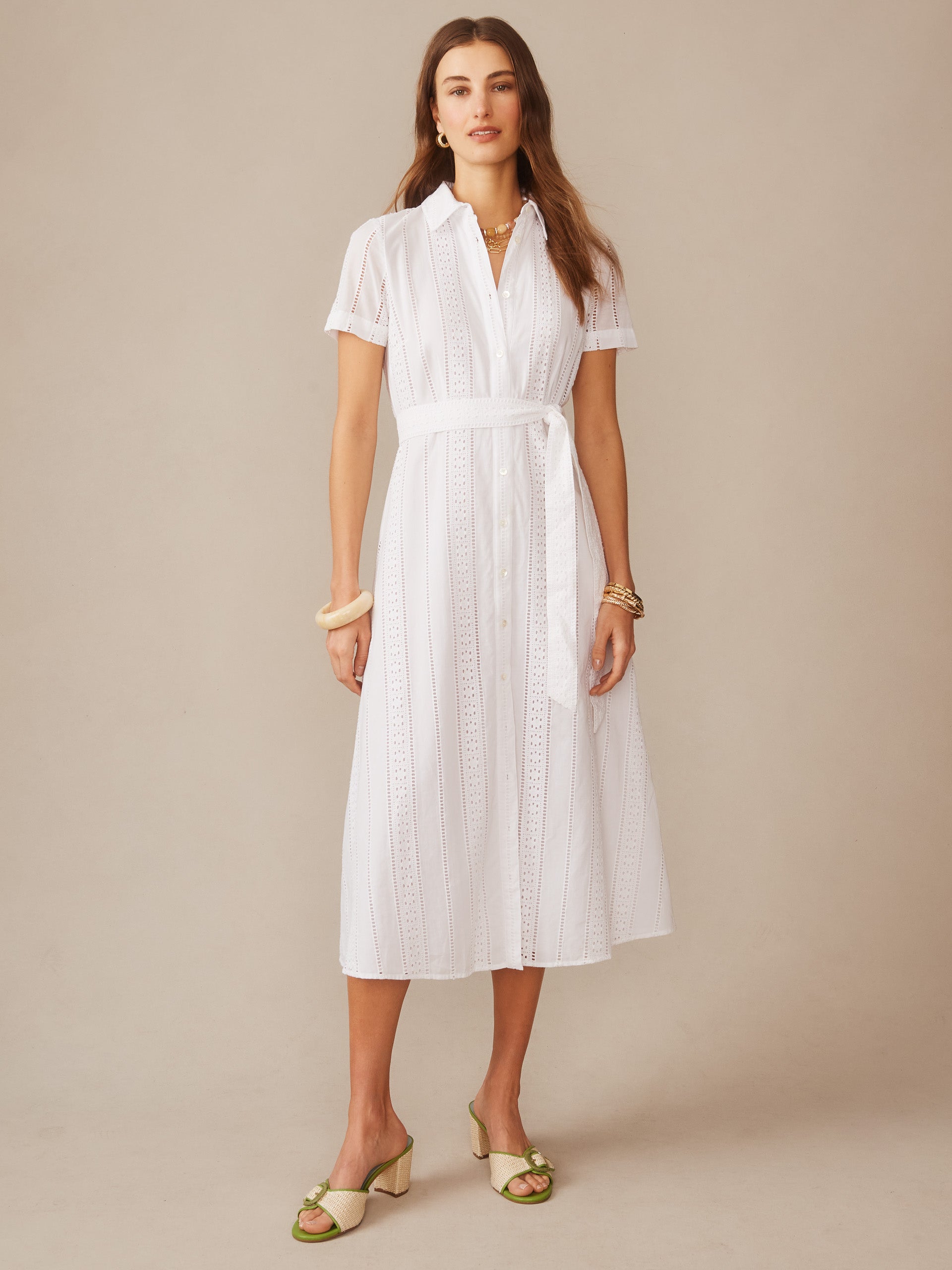 Woman wearing a white Kalinda Dress in Eyelet by J.McLaughlin, featuring a belted waist and button-down front, showcasing effortlessly stylish and enduring designs.