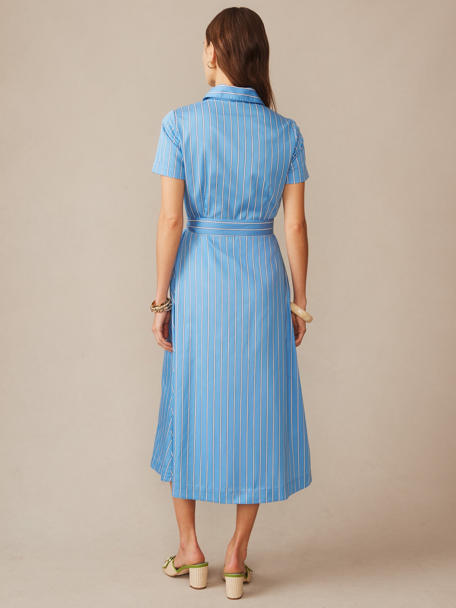 Back view of a model wearing the Kalinda Dress in Stripe by J.McLaughlin, featuring a blue striped pattern and short sleeves, showcasing effortlessly stylish and enduring designs.