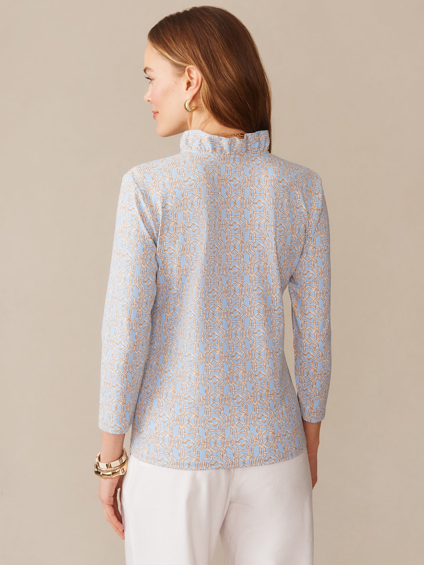 Woman wearing a J.McLaughlin Kate Ruffle Top in Bamboo Lane, featuring a delicate geometric pattern in soft blue and tan hues, embodying effortlessly stylish and enduring designs.