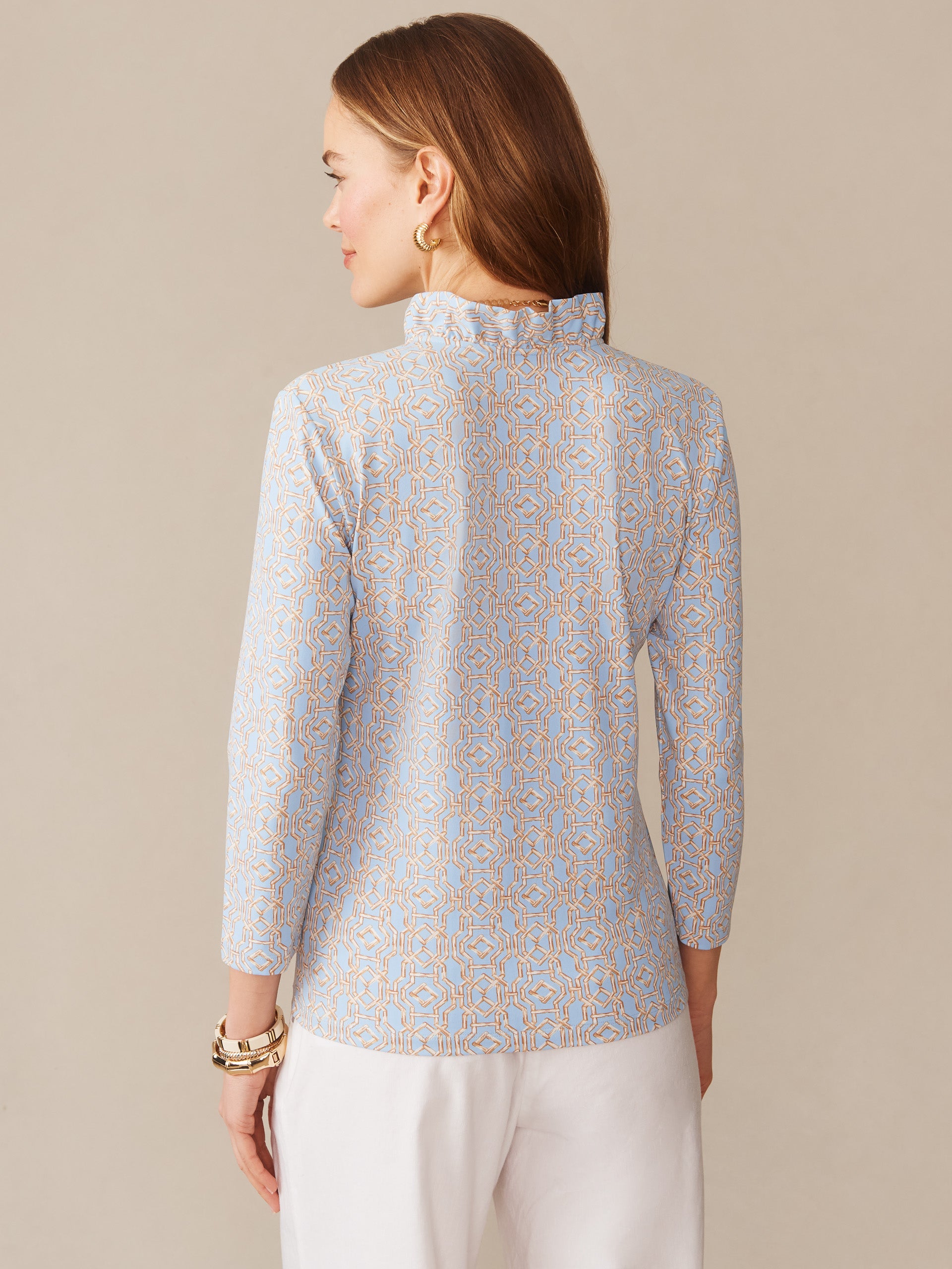 Woman wearing a J.McLaughlin Kate Ruffle Top in Bamboo Lane, featuring a delicate geometric pattern in soft blue and tan hues, embodying effortlessly stylish and enduring designs.