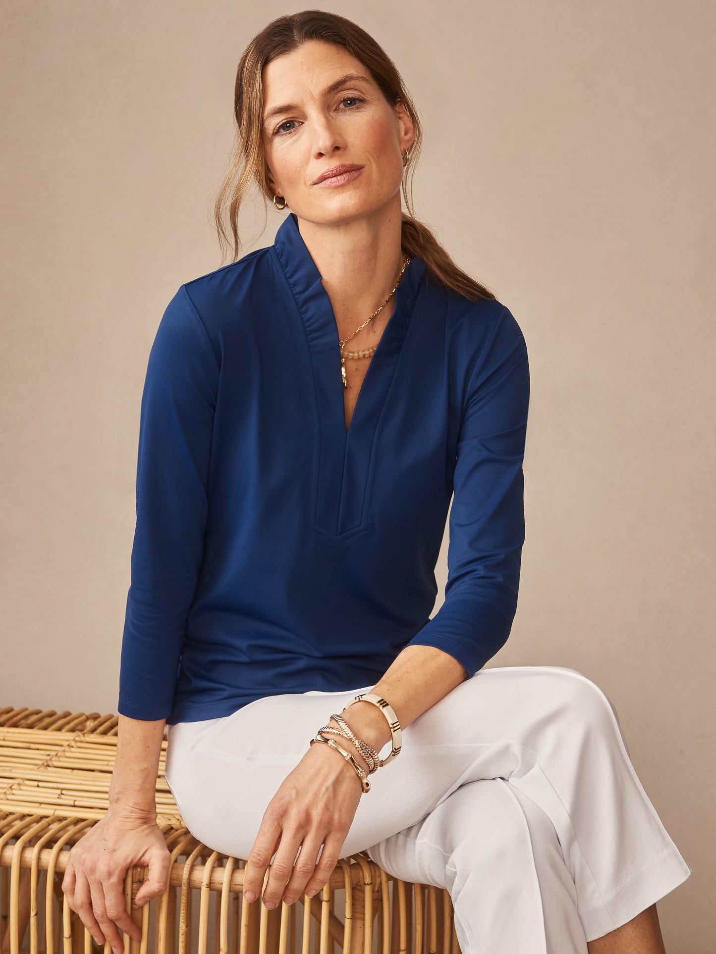 Woman wearing a nautical navy Kate Ruffle Top by J.McLaughlin paired with white pants, embodying effortlessly stylish, enduring designs and innovative fabrics for a life well-lived.