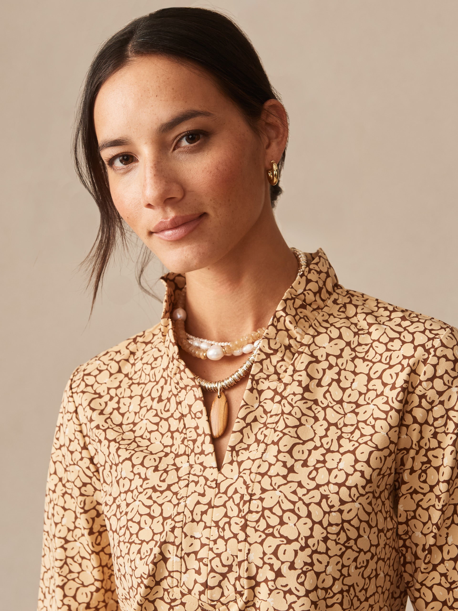 Woman wearing Kate Ruffle Top in Celandine by J.McLaughlin, featuring a delicate floral pattern and ruffled collar, showcasing effortlessly stylish, enduring designs in innovative fabrics. A destination for defining style. Life, Well-Lived.
