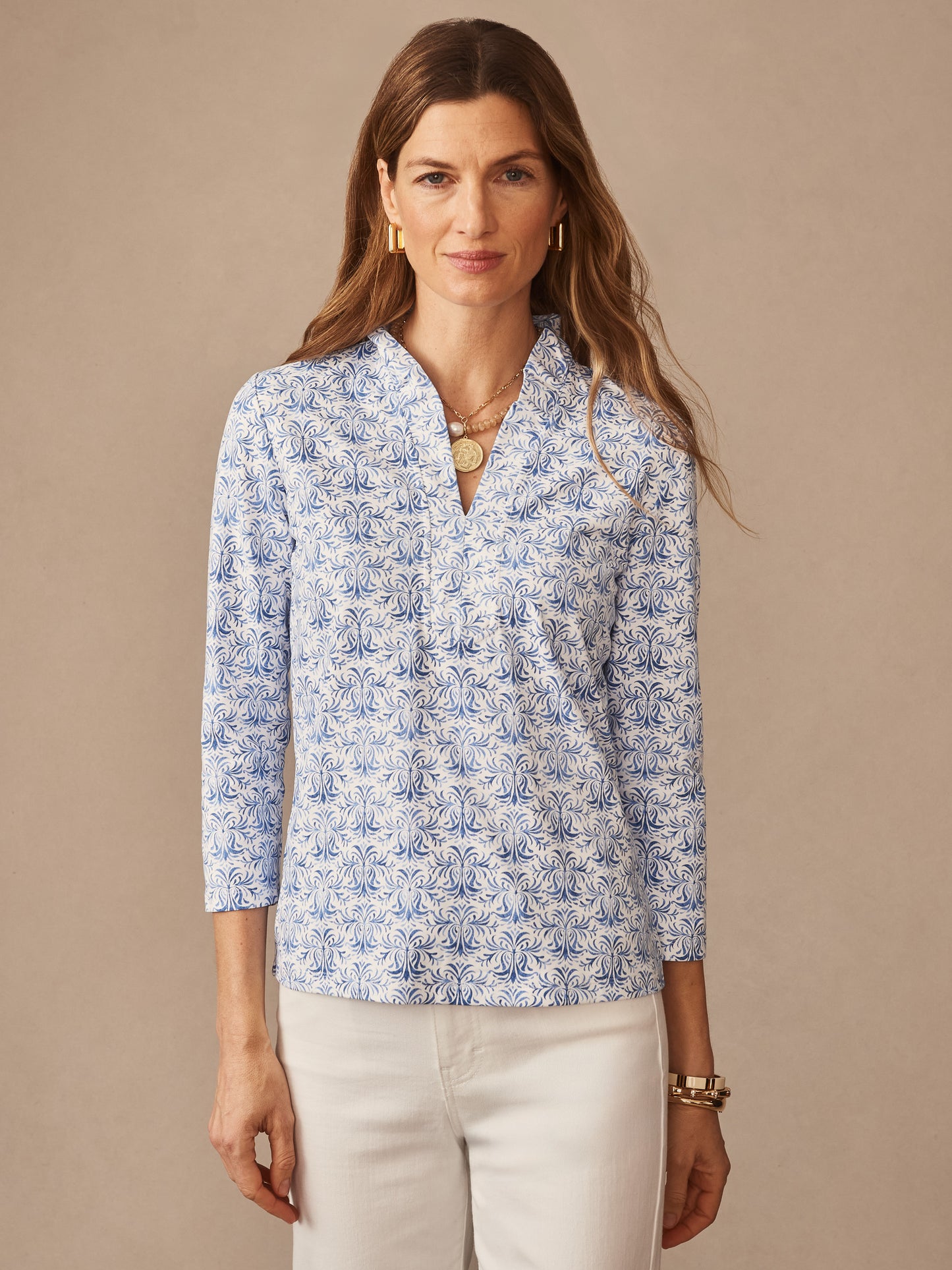 Woman wearing a blue and white patterned blouse with three-quarter sleeves paired with white denim, showcasing the Kate Ruffle Top in Mini Drawing Room by J.McLaughlin, embodying effortlessly stylish, enduring designs and innovative fabrics.