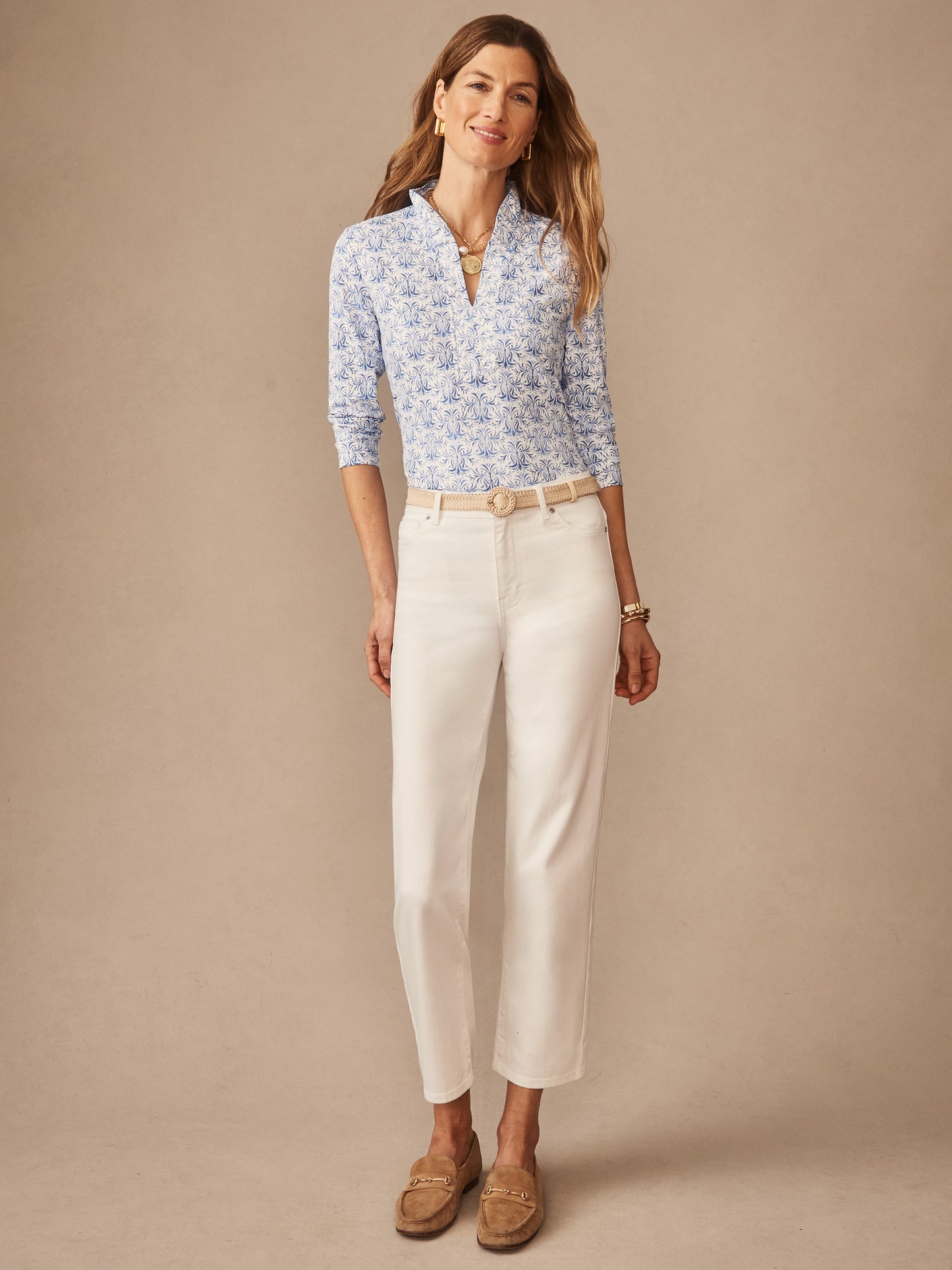 Woman wearing a blue and white Kate Ruffle Top in Mini Drawing Room with white denim pants and neutral loafers, showcasing effortlessly stylish, enduring designs by J.McLaughlin, a destination for defining style. Life, Well-Lived.
