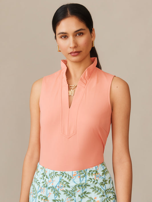 Model wearing the Kate Sleeveless Ruffle Top by J.McLaughlin in tropical coral, paired with floral print bottoms, showcasing effortlessly stylish, enduring designs with a legacy of timeless fashion.