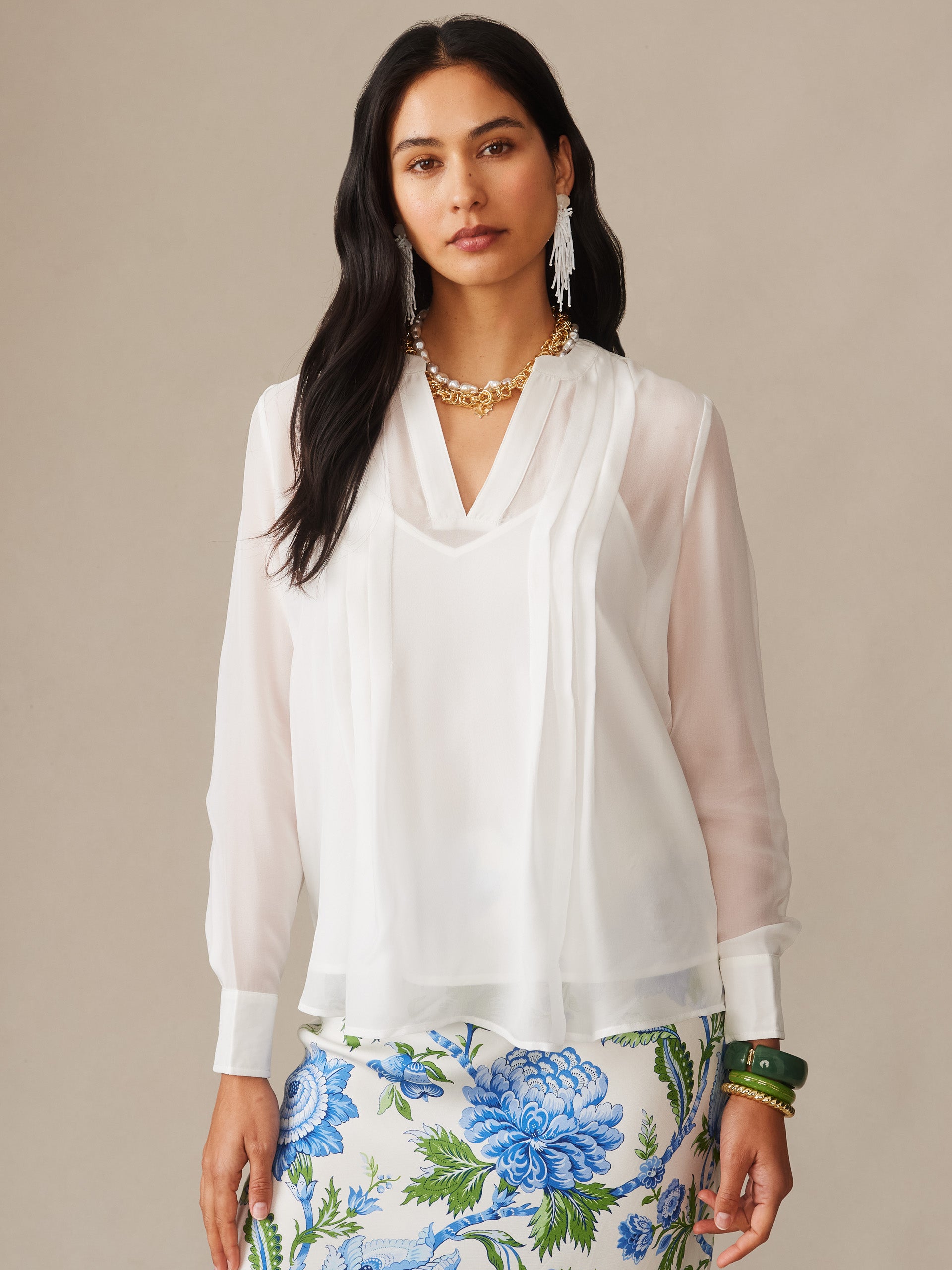 Woman wearing an off-white Katherine Silk Chiffon Blouse by J.McLaughlin paired with a floral skirt, embodying effortlessly stylish and enduring designs for a life well-lived.