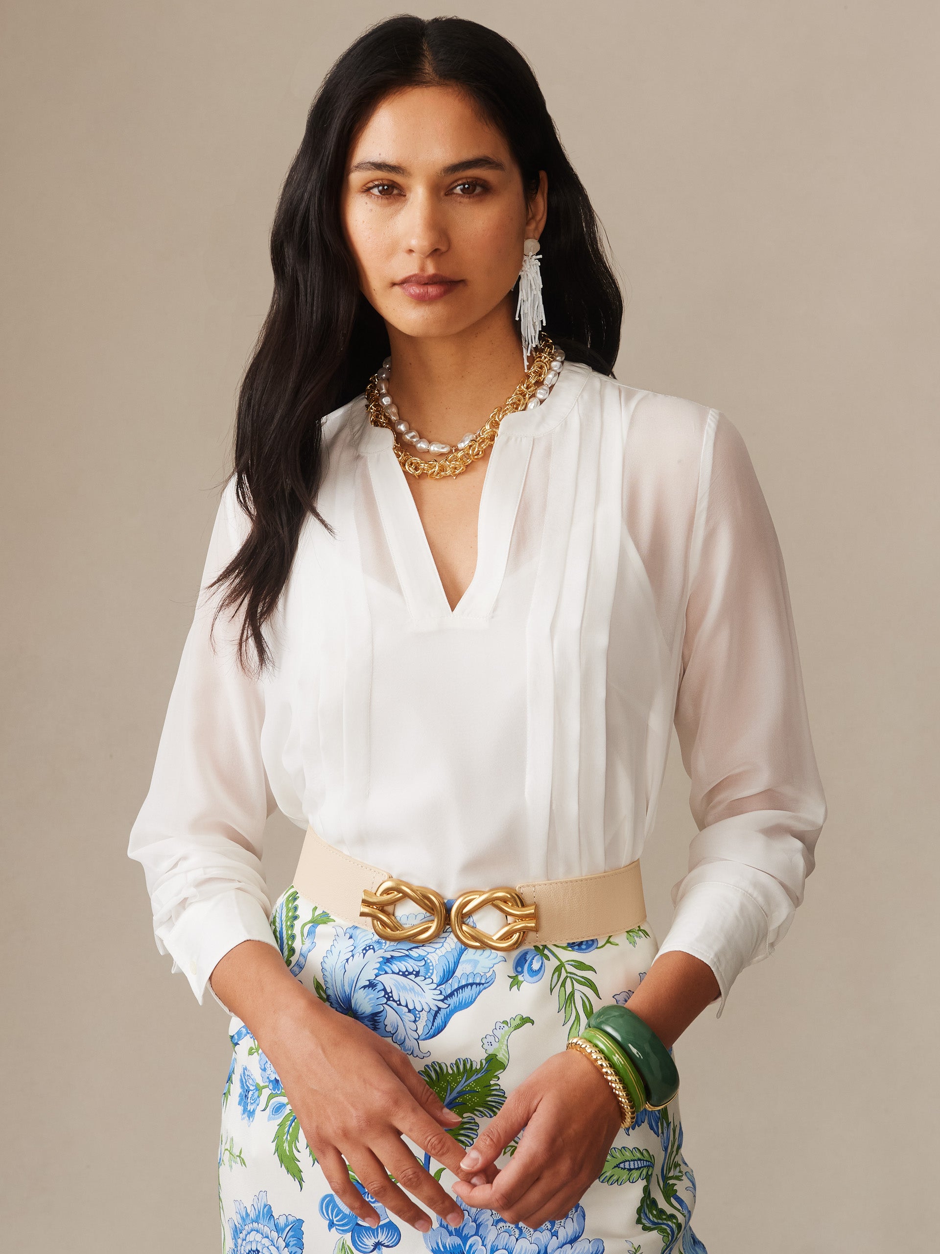 Woman wearing an off-white Katherine Silk Chiffon Blouse by J.McLaughlin paired with a floral skirt and gold accessories, embodying effortlessly stylish and enduring designs.