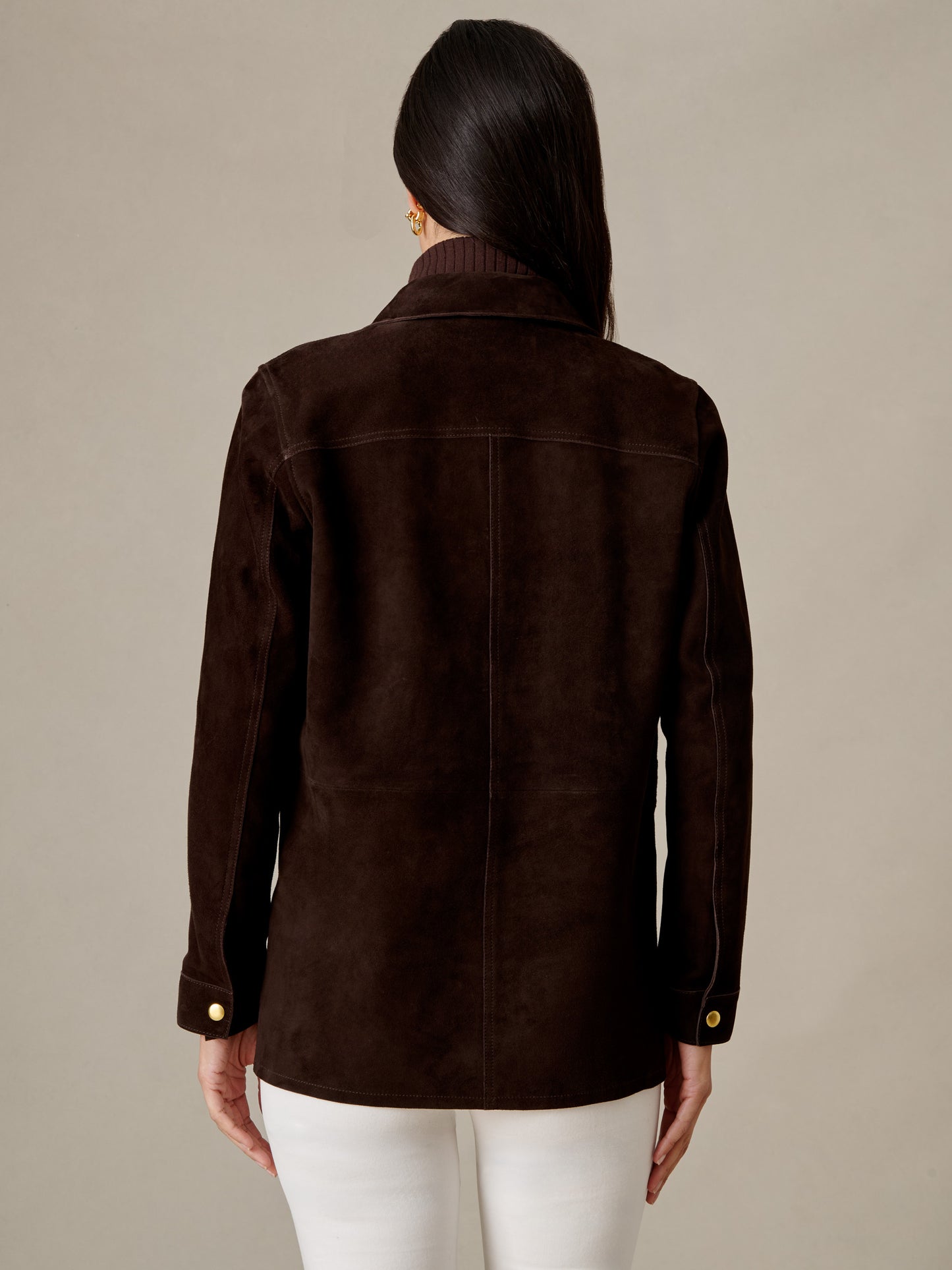 Back view of model wearing the Kavya Suede Jacket by J.McLaughlin in rich brown goat suede with white pants for timeless style