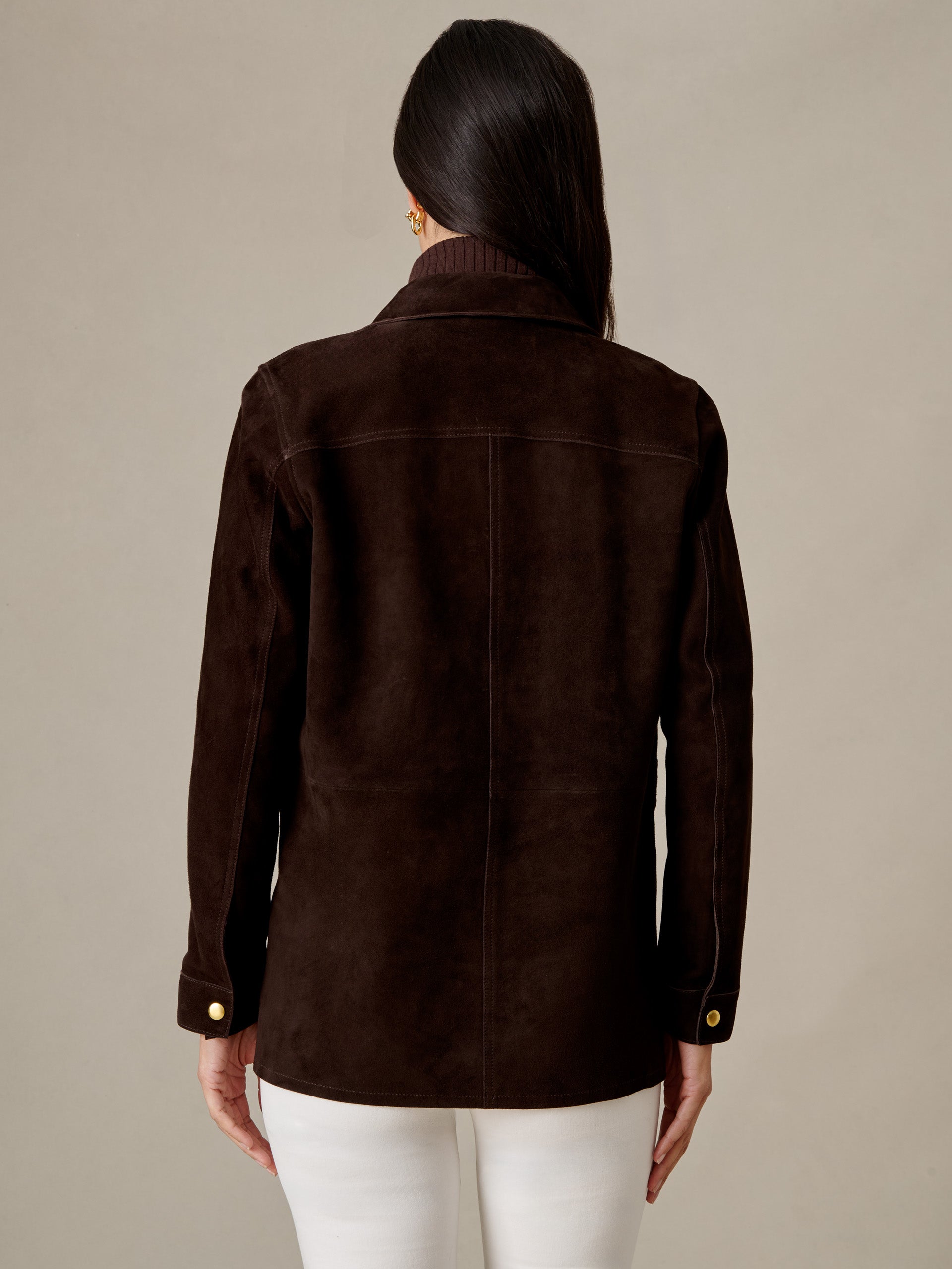 Back view of model wearing the Kavya Suede Jacket by J.McLaughlin in rich brown goat suede with white pants for timeless style