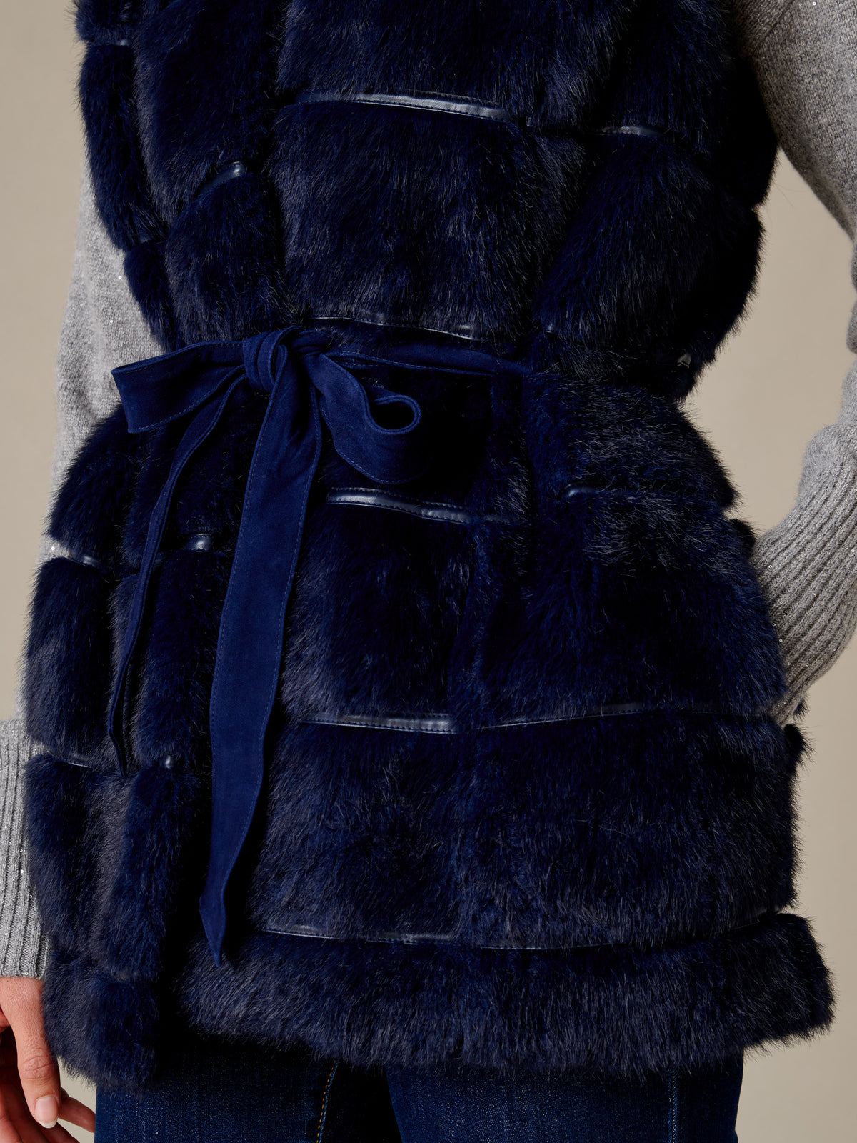 Keley Faux Fur Vest by J.McLaughlin in dark navy plush faux fur with a suede tie belt layered over a gray knit sweater
