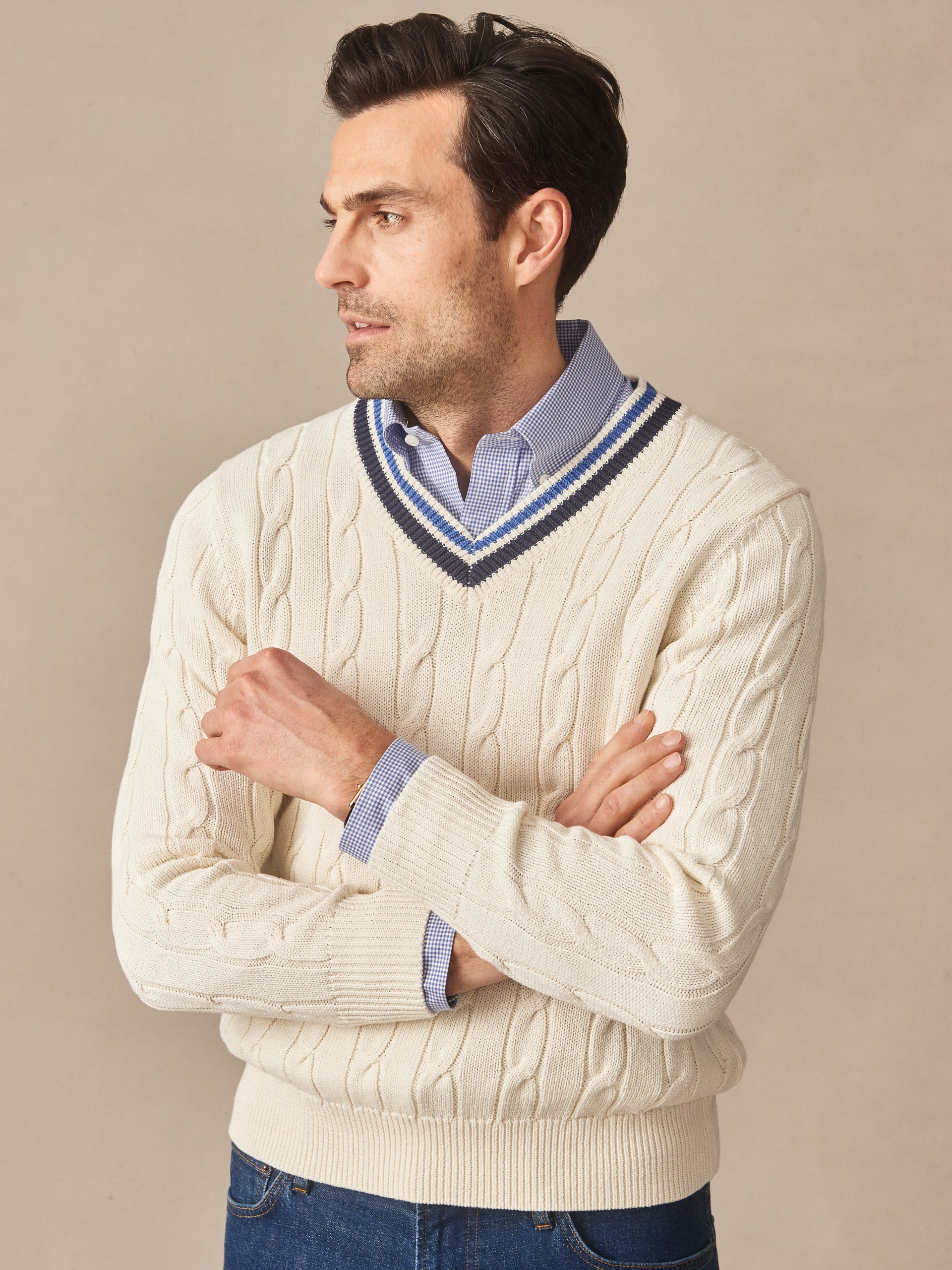 Man wearing an off-white Kent Sweater by J.McLaughlin over a blue checkered shirt, showcasing effortlessly stylish, enduring designs and innovative fabrics for a legacy of timeless fashion.