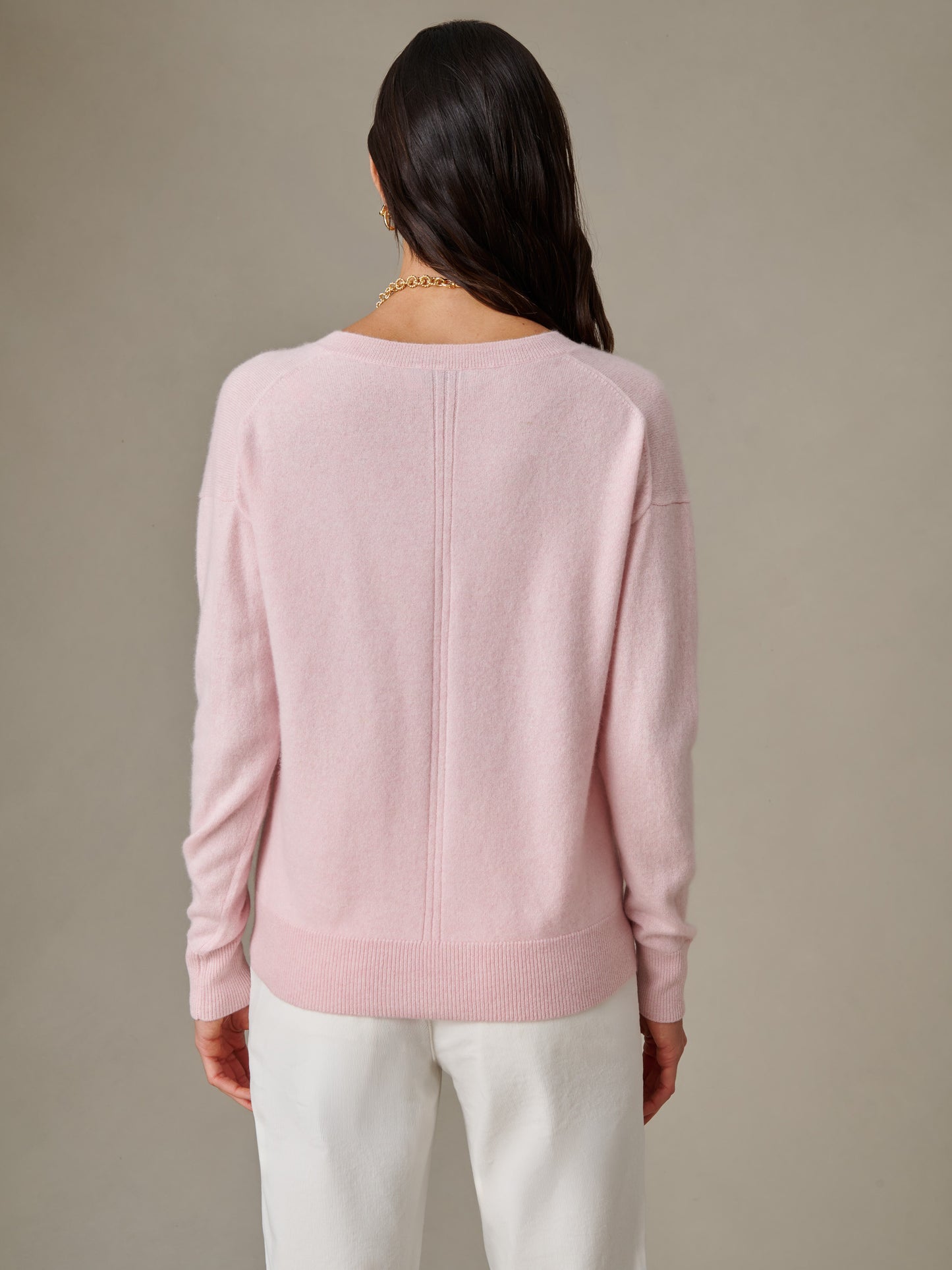 Woman wearing a soft pink Kerry Cashmere Sweater by J.McLaughlin, showcasing its timeless design and impeccable craftsmanship for enduring style.