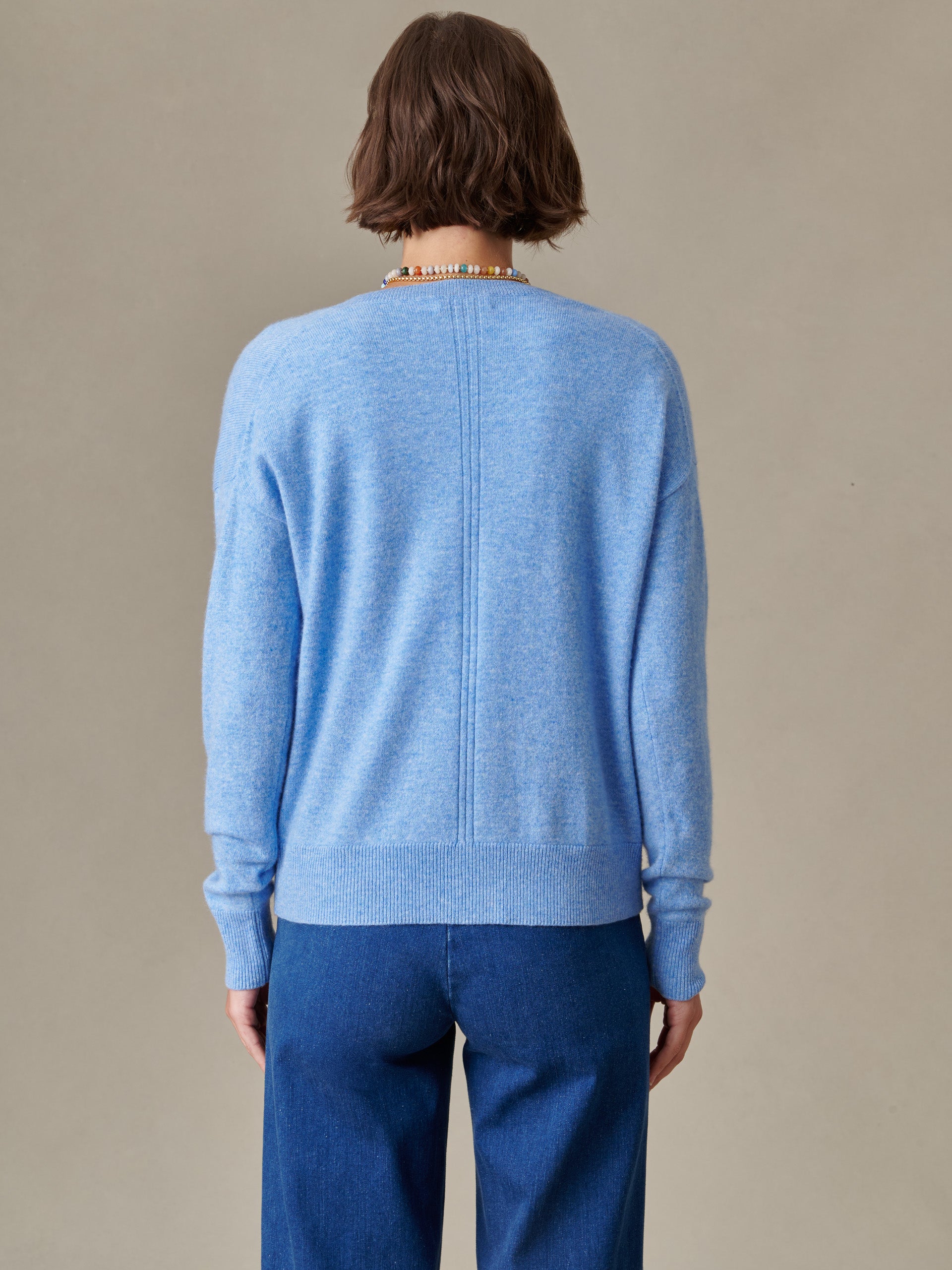 Back view of a person wearing a soft blue Kerry Cashmere Sweater by J.McLaughlin paired with dark blue pants, reflecting effortlessly stylish and enduring designs.