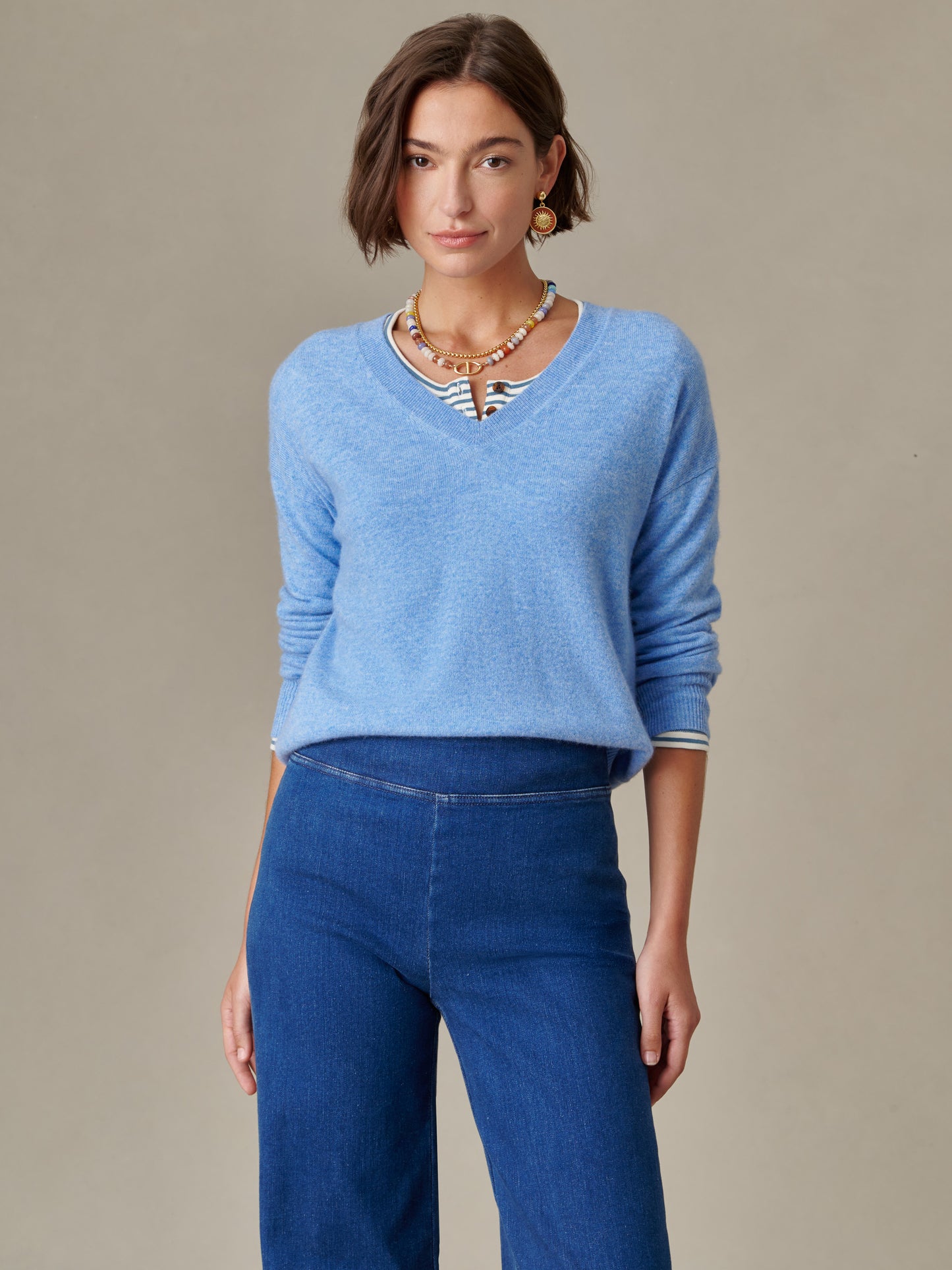 Woman wearing a soft blue Kerry Cashmere Sweater by J.McLaughlin paired with blue pants, styled with layered necklaces and earrings for an effortlessly stylish look.