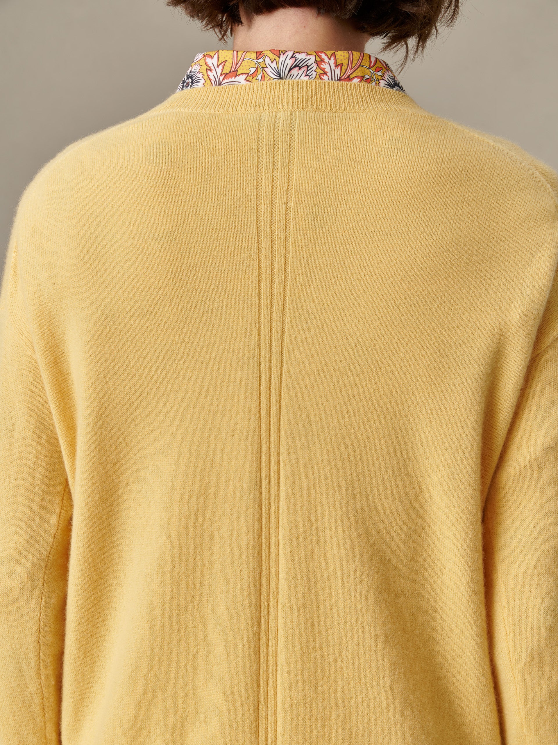 Back view of a person wearing a Kerry Cashmere Sweater in soft yellow by J.McLaughlin, showcasing its smooth texture and timeless, enduring design.