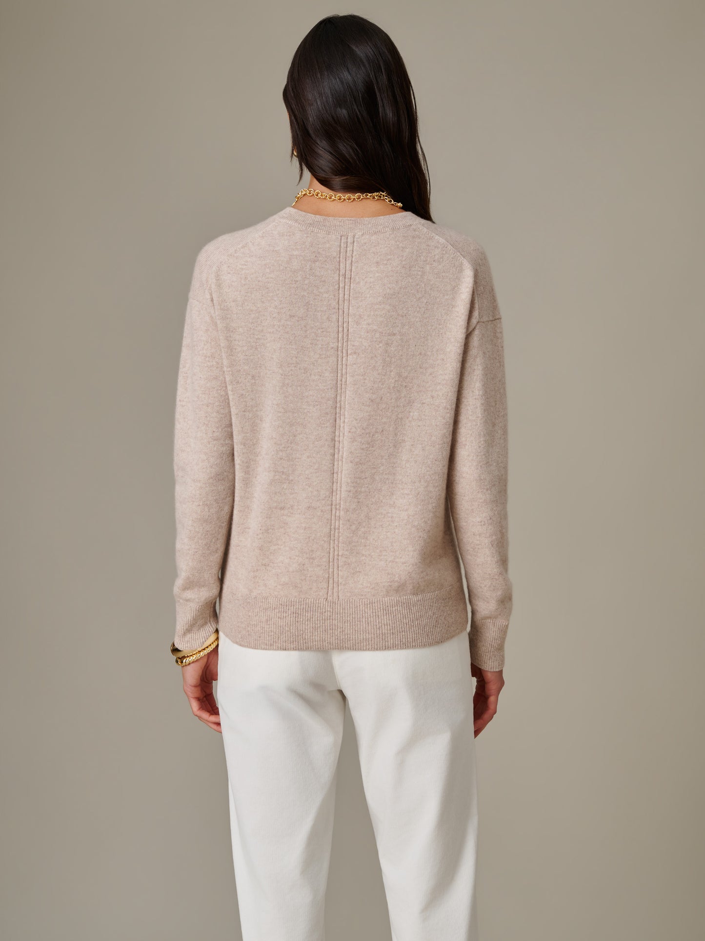 Woman wearing a beige Kerry Cashmere Sweater by J.McLaughlin, styled with white pants, showcasing timeless, effortlessly stylish design and enduring comfort.