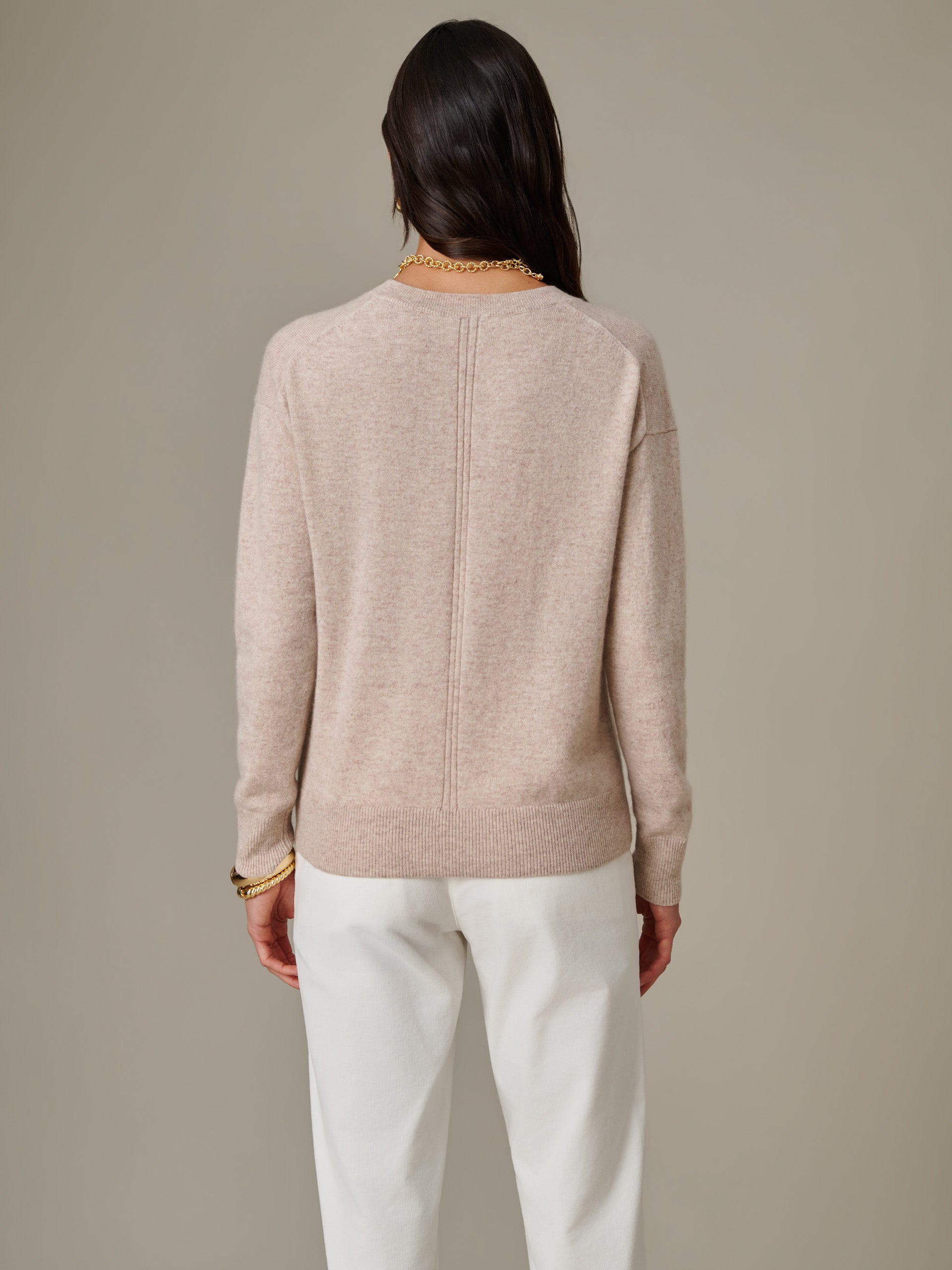 Woman wearing a beige Kerry Cashmere Sweater by J.McLaughlin, styled with white pants, showcasing timeless, effortlessly stylish design and enduring comfort.