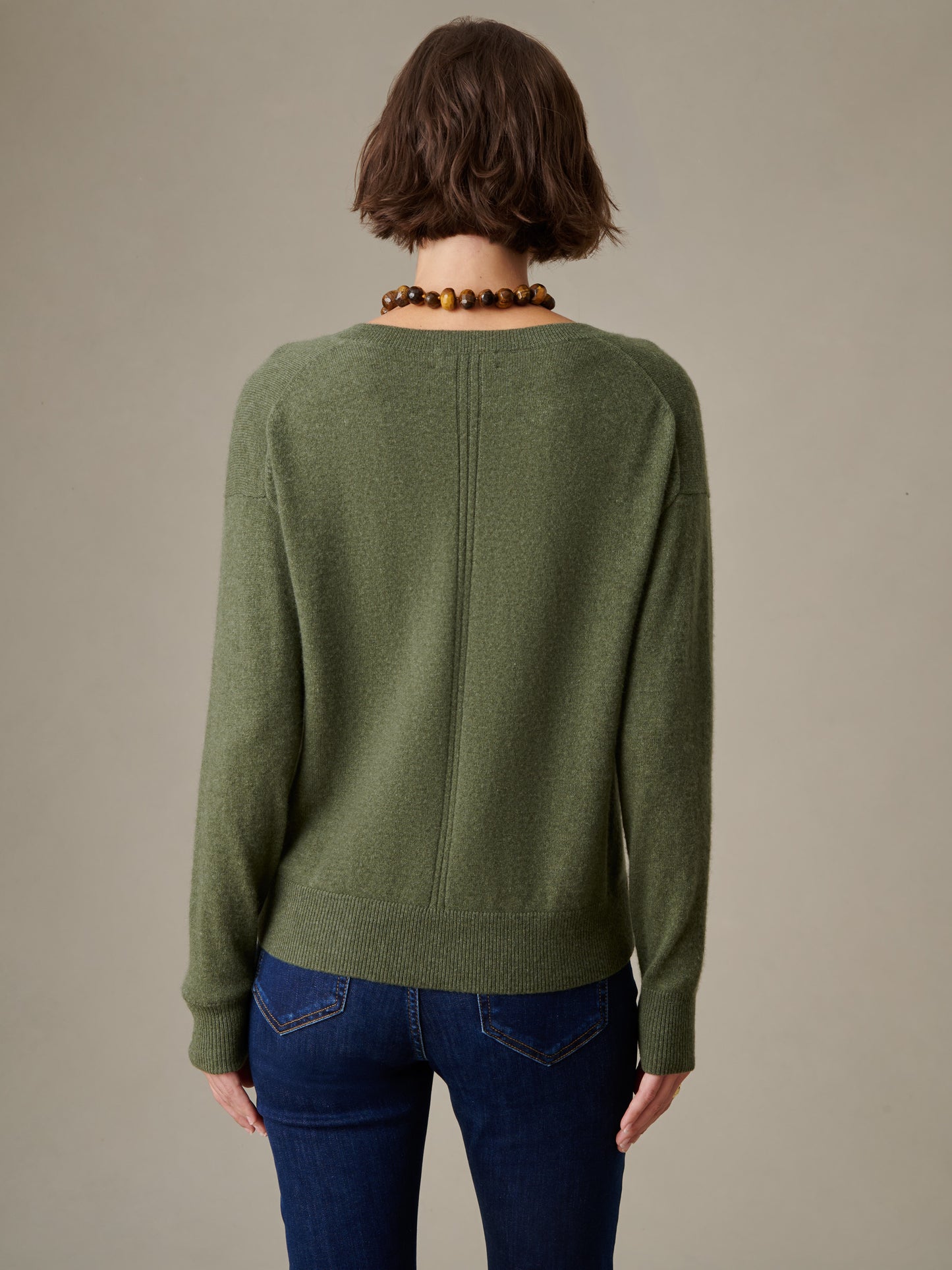 Back view of a person wearing a green Kerry Cashmere Sweater by J.McLaughlin paired with dark blue jeans, showcasing the sweater’s timeless, effortlessly stylish design.