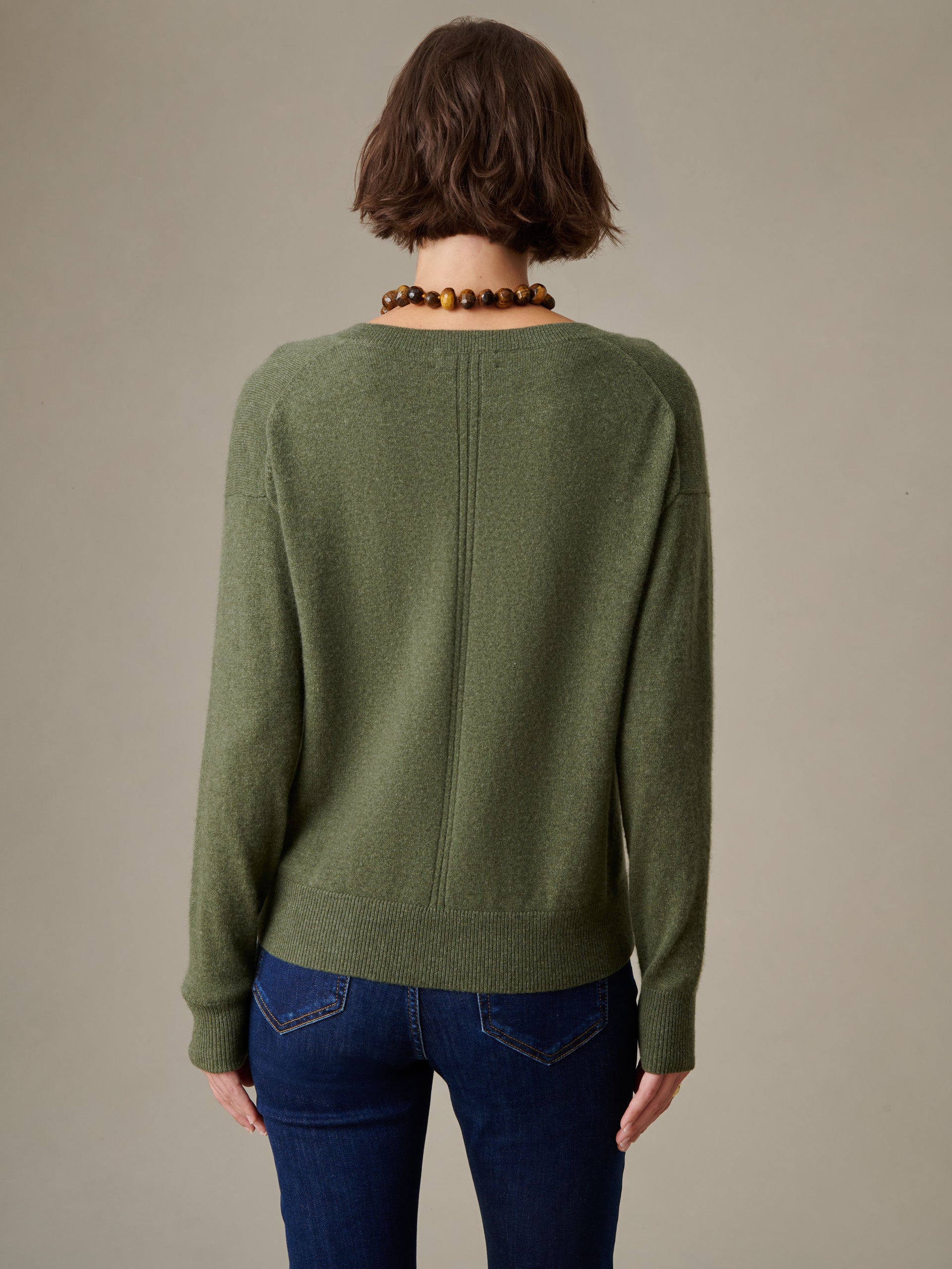 Back view of a person wearing a green Kerry Cashmere Sweater by J.McLaughlin paired with dark blue jeans, showcasing the sweater’s timeless, effortlessly stylish design.