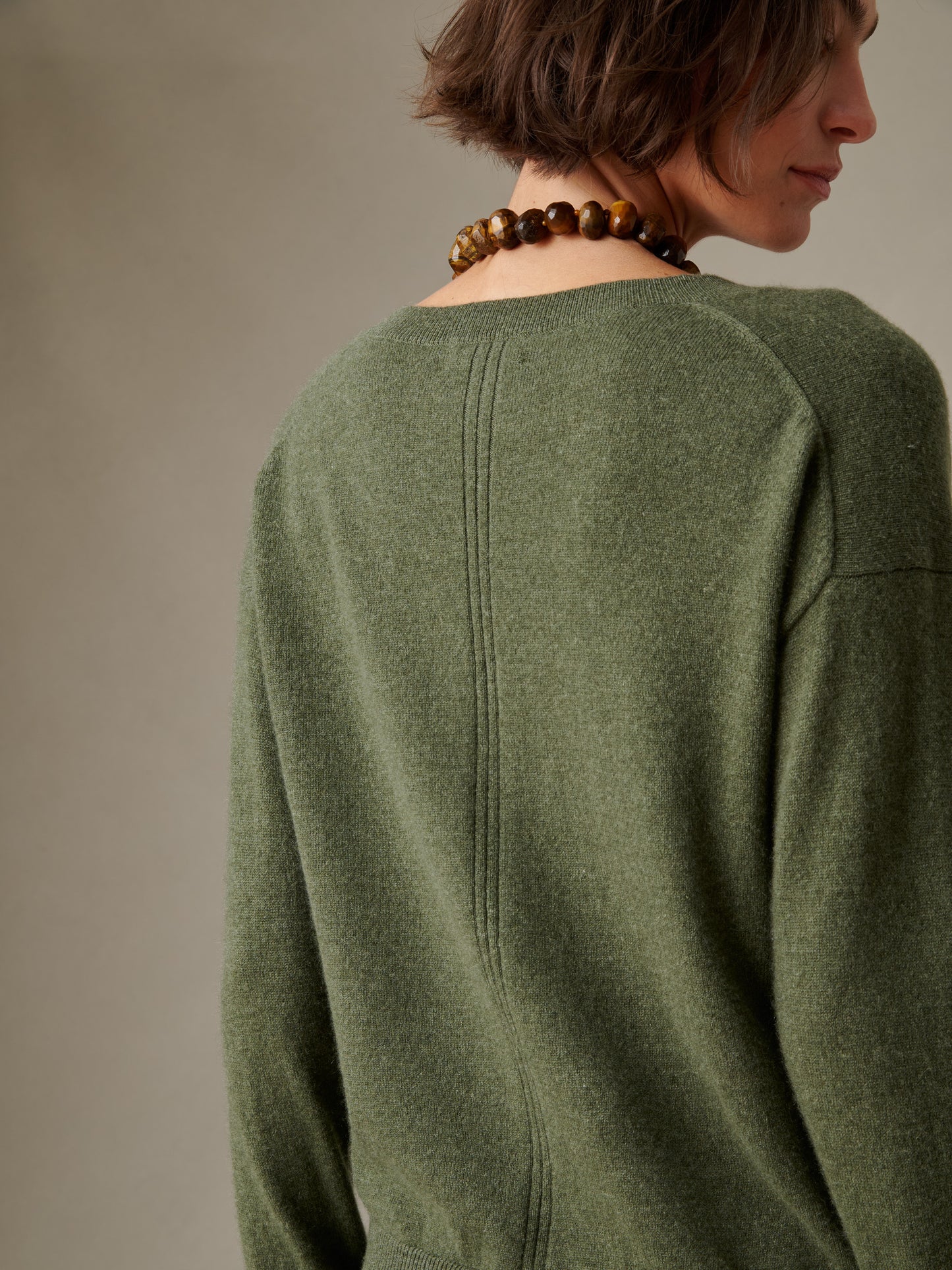 Back view of a woman wearing a soft green Kerry Cashmere Sweater by J.McLaughlin, showcasing its impeccable craftsmanship and timeless, enduring design.