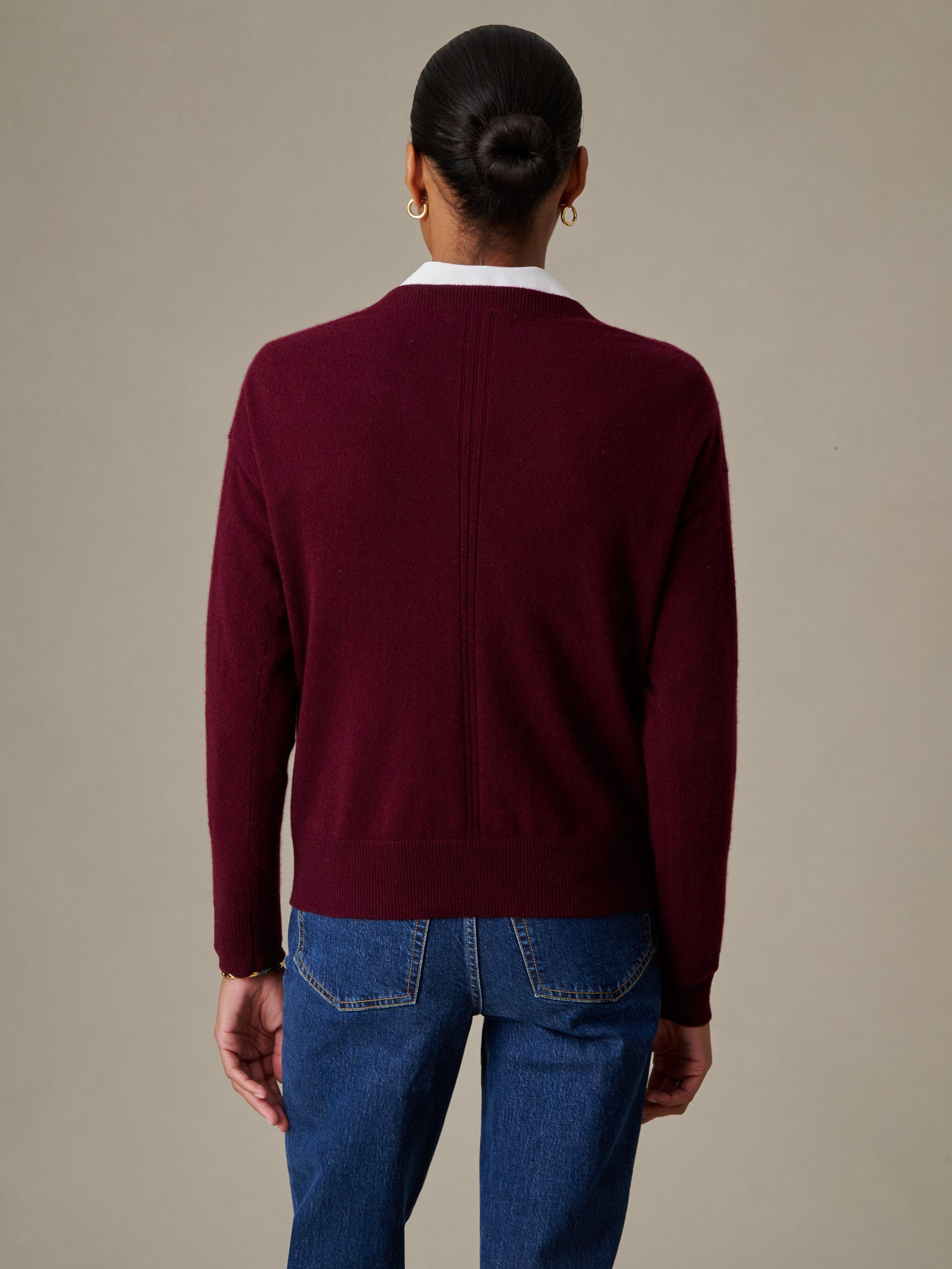 Woman seen from behind wearing a deep burgundy Kerry Cashmere Sweater by J.McLaughlin paired with blue jeans, showcasing timeless style and impeccable craftsmanship.
