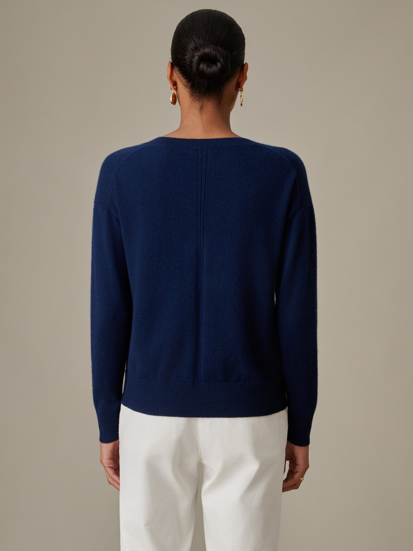 Back view of a person wearing a navy Kerry Cashmere Sweater by J.McLaughlin paired with white pants, showcasing a timeless and effortlessly stylish sweater design.