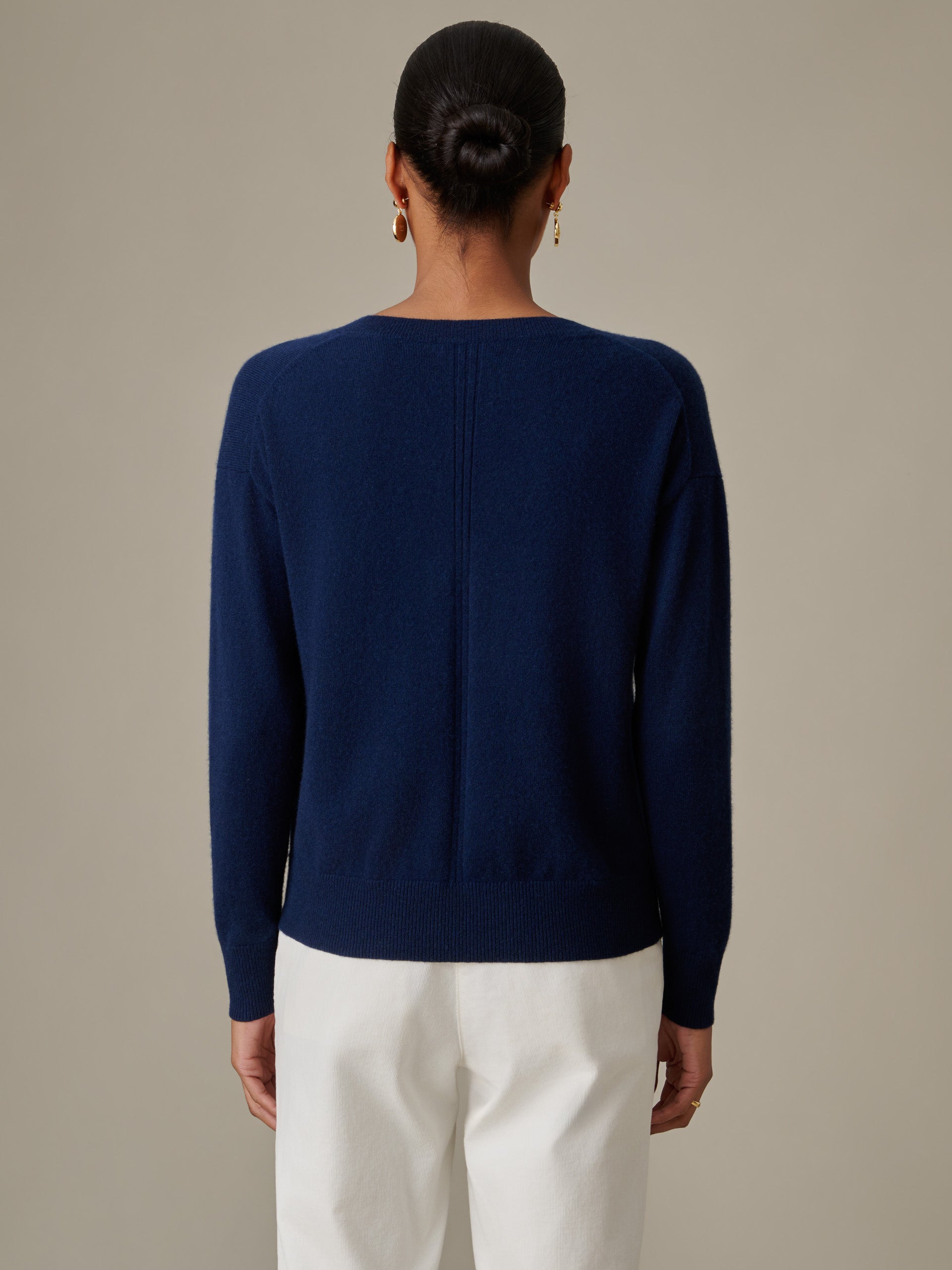 Back view of a person wearing a navy Kerry Cashmere Sweater by J.McLaughlin paired with white pants, showcasing a timeless and effortlessly stylish sweater design.