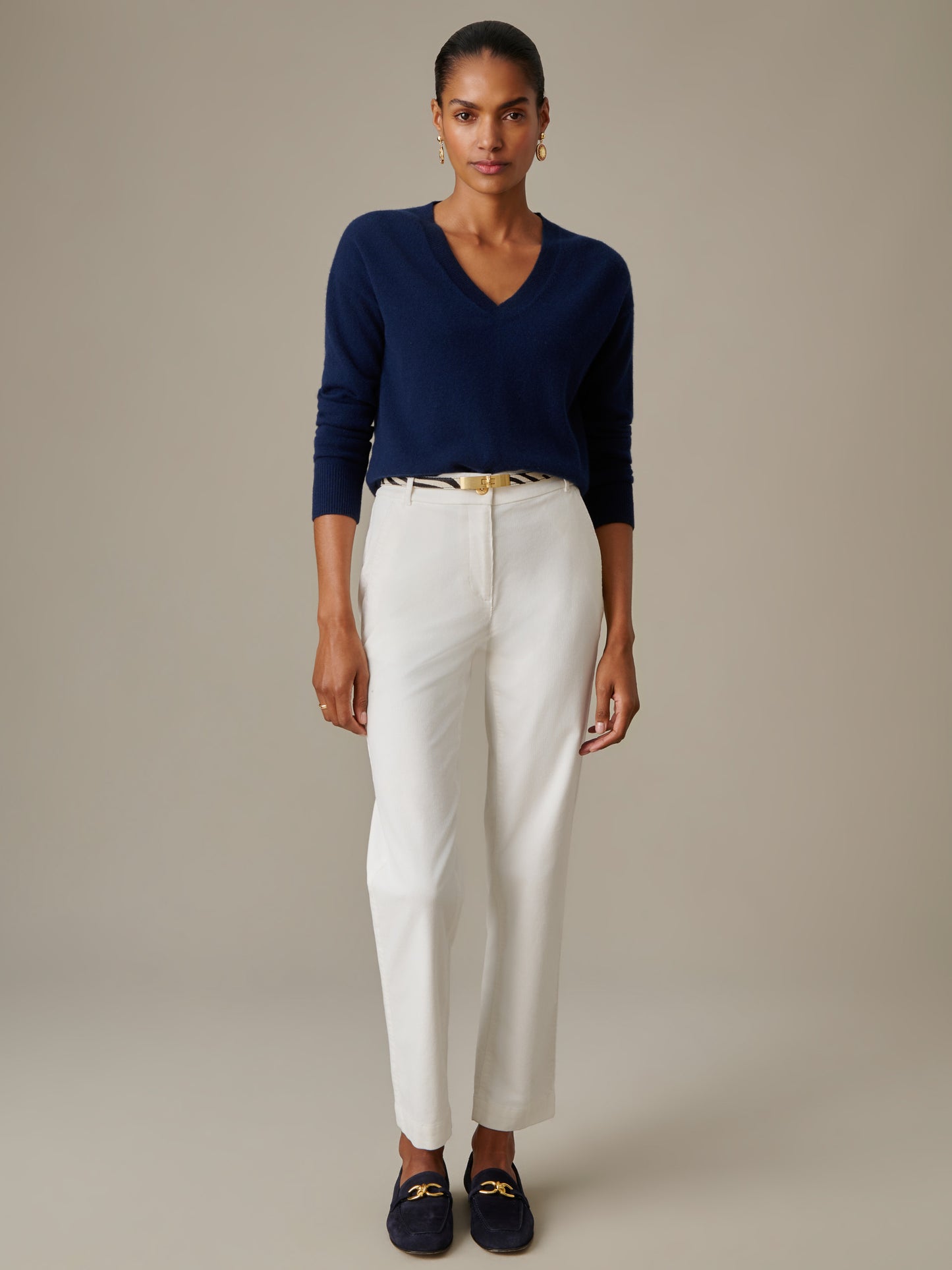 Woman wearing a navy Kerry Cashmere Sweater by J.McLaughlin paired with white pants and navy loafers, showcasing timeless style and enduring design essentials.