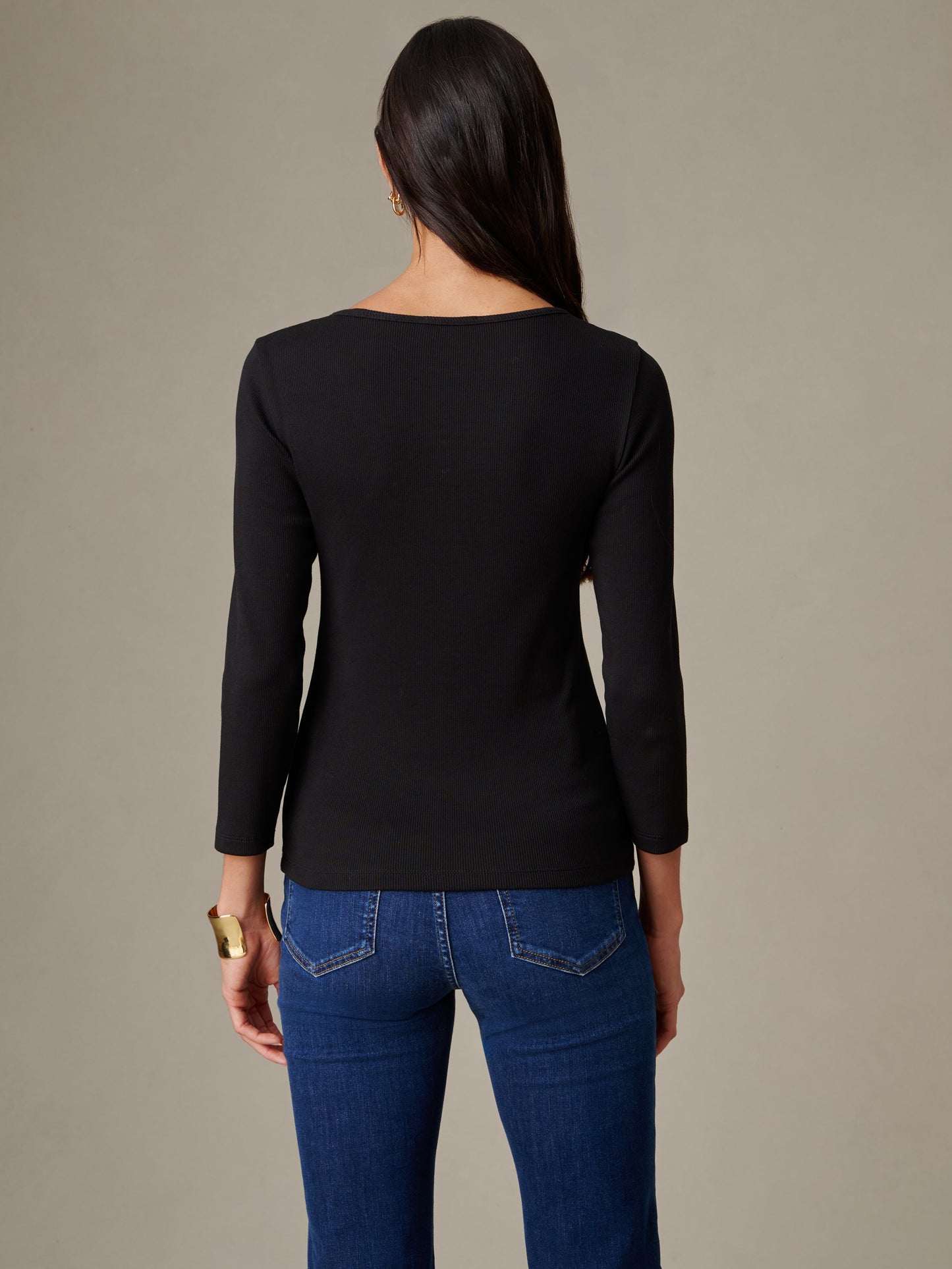 Woman seen from the back wearing a black Kit Ribbed Tee by J.McLaughlin paired with blue jeans, showcasing timeless style and impeccable craftsmanship perfect for an enduring wardrobe.