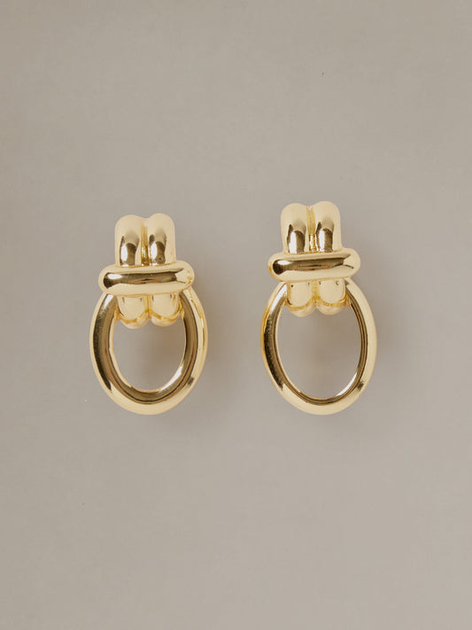 J.McLaughlin Knot Earrings featuring polished gold tone looped knot design for an effortlessly stylish and timeless accessory on a neutral background
