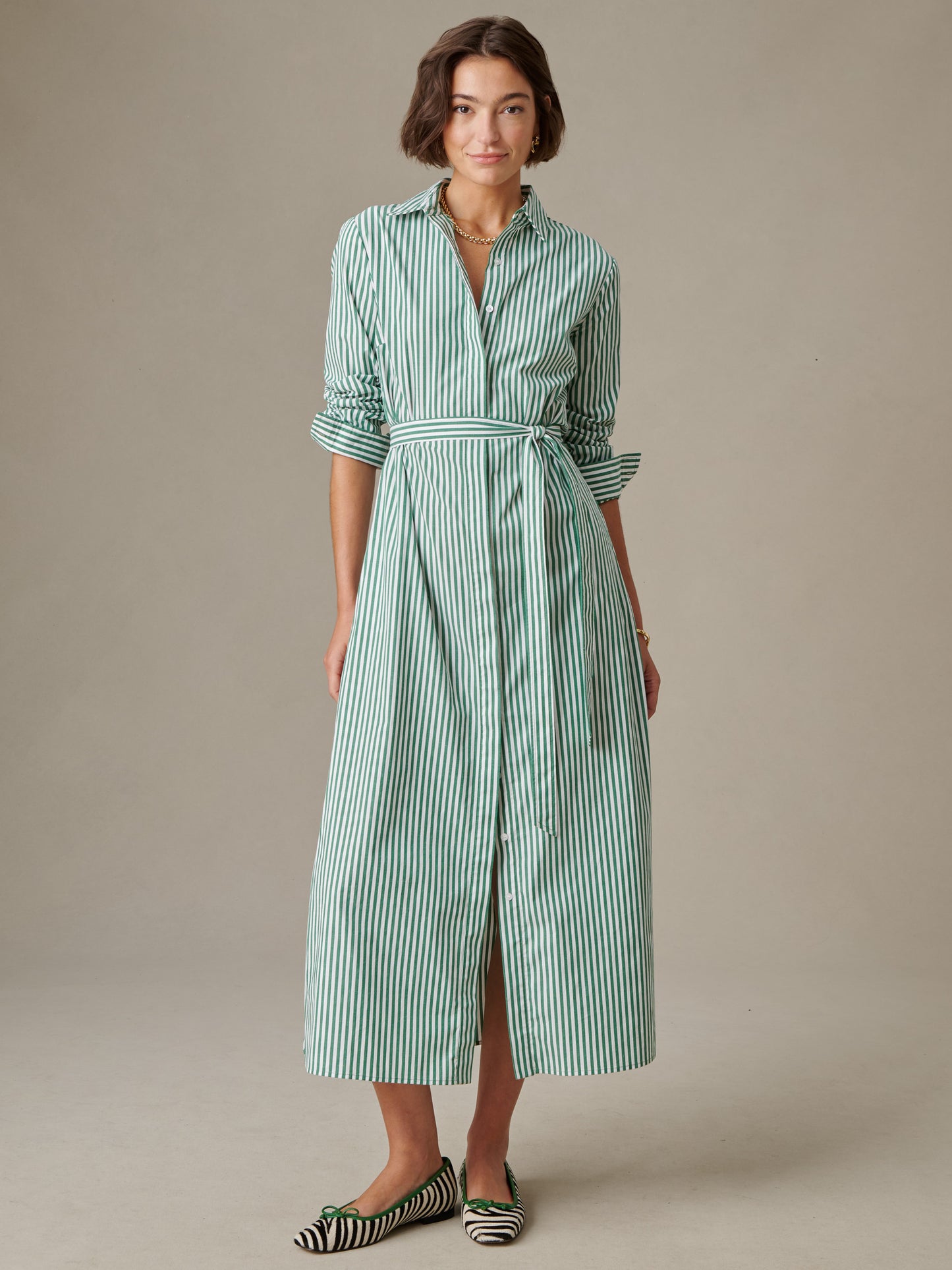 Woman wearing a green and white striped Leighton Dress in Stripe by J.McLaughlin, styled with rolled-up sleeves and matching striped shoes, exuding timeless, effortless style.
