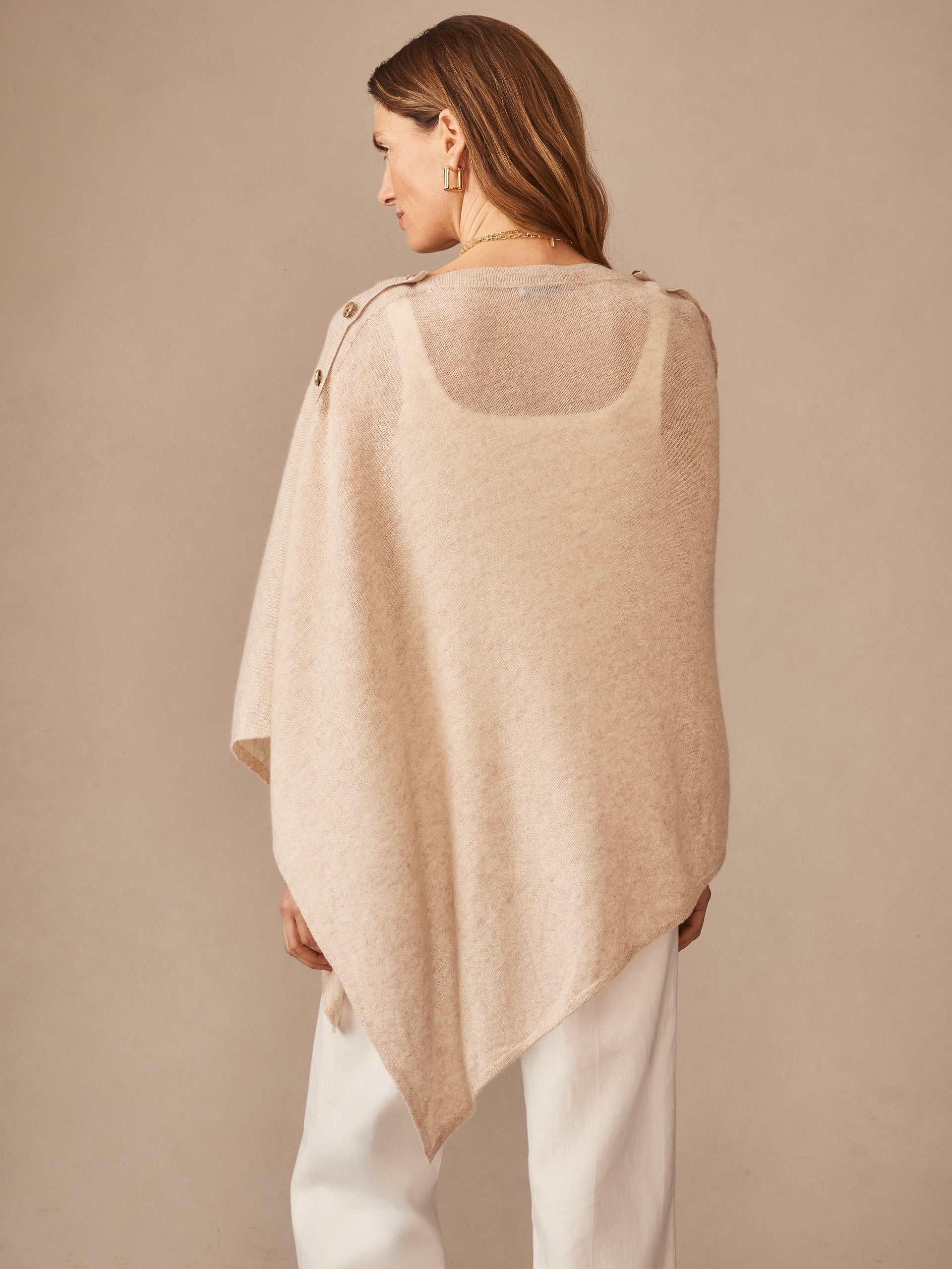 Woman wearing a tan Leila Cashmere Poncho by J.McLaughlin, showcasing effortlessly stylish, enduring designs crafted from innovative fabrics for a legacy of timeless fashion.
