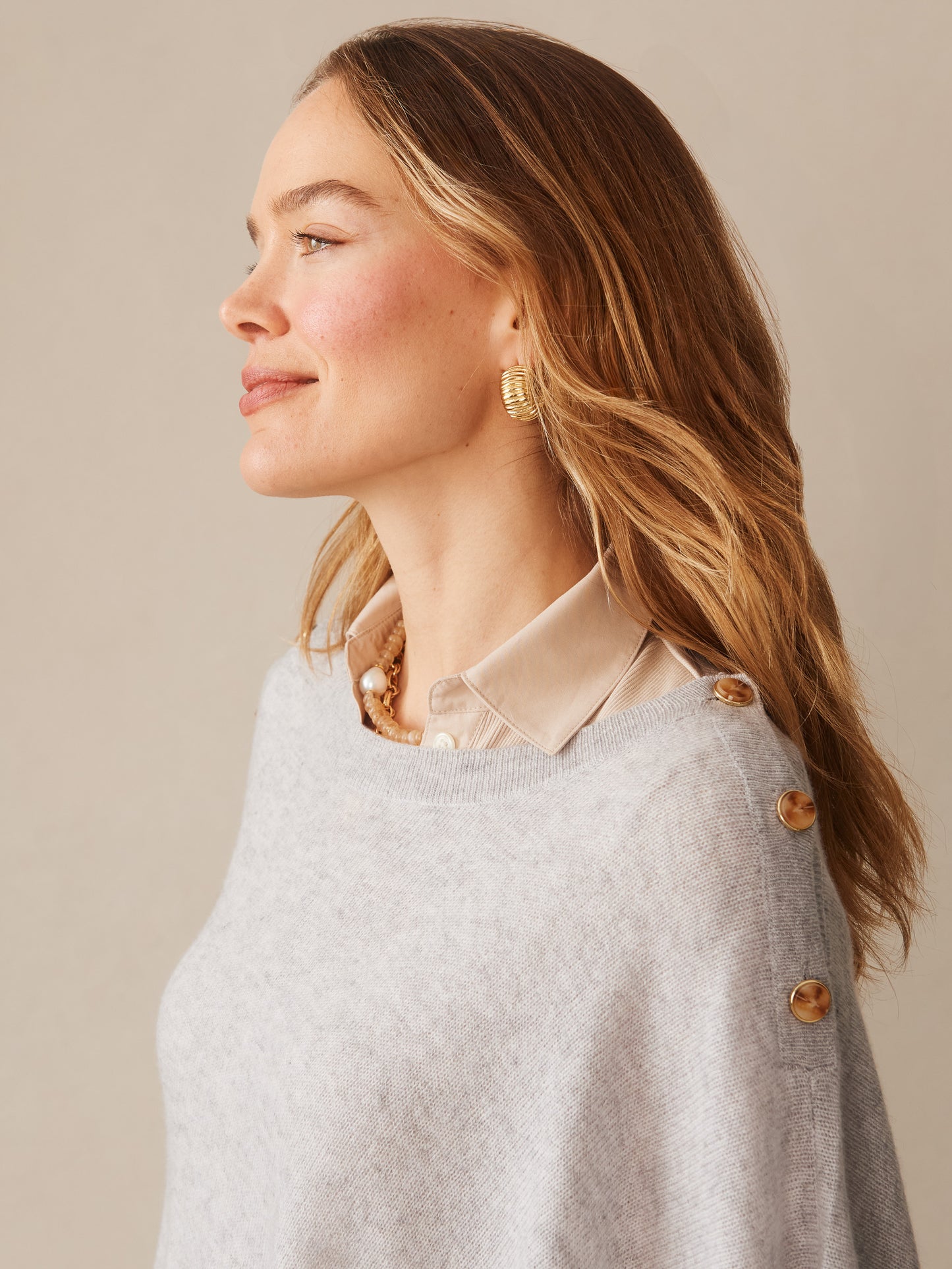 Woman wearing a soft grey Leila Cashmere Poncho by J.McLaughlin, styled over a beige collared blouse, showcasing effortless style and enduring design in a timeless look.