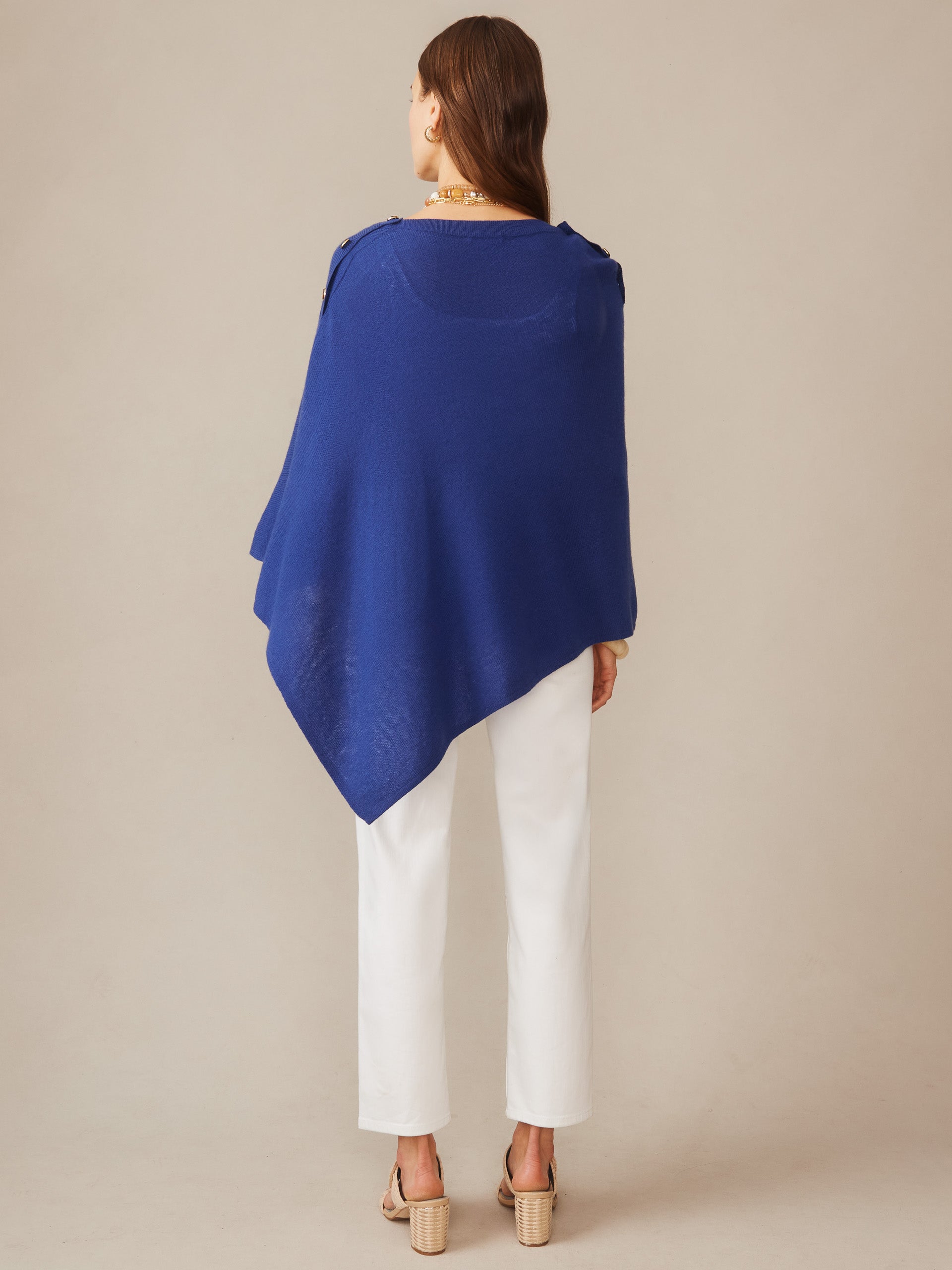 Woman wearing a nautical navy Leila Cashmere Poncho paired with white pants and beige sandals, showcasing effortlessly stylish, enduring designs by J.McLaughlin.