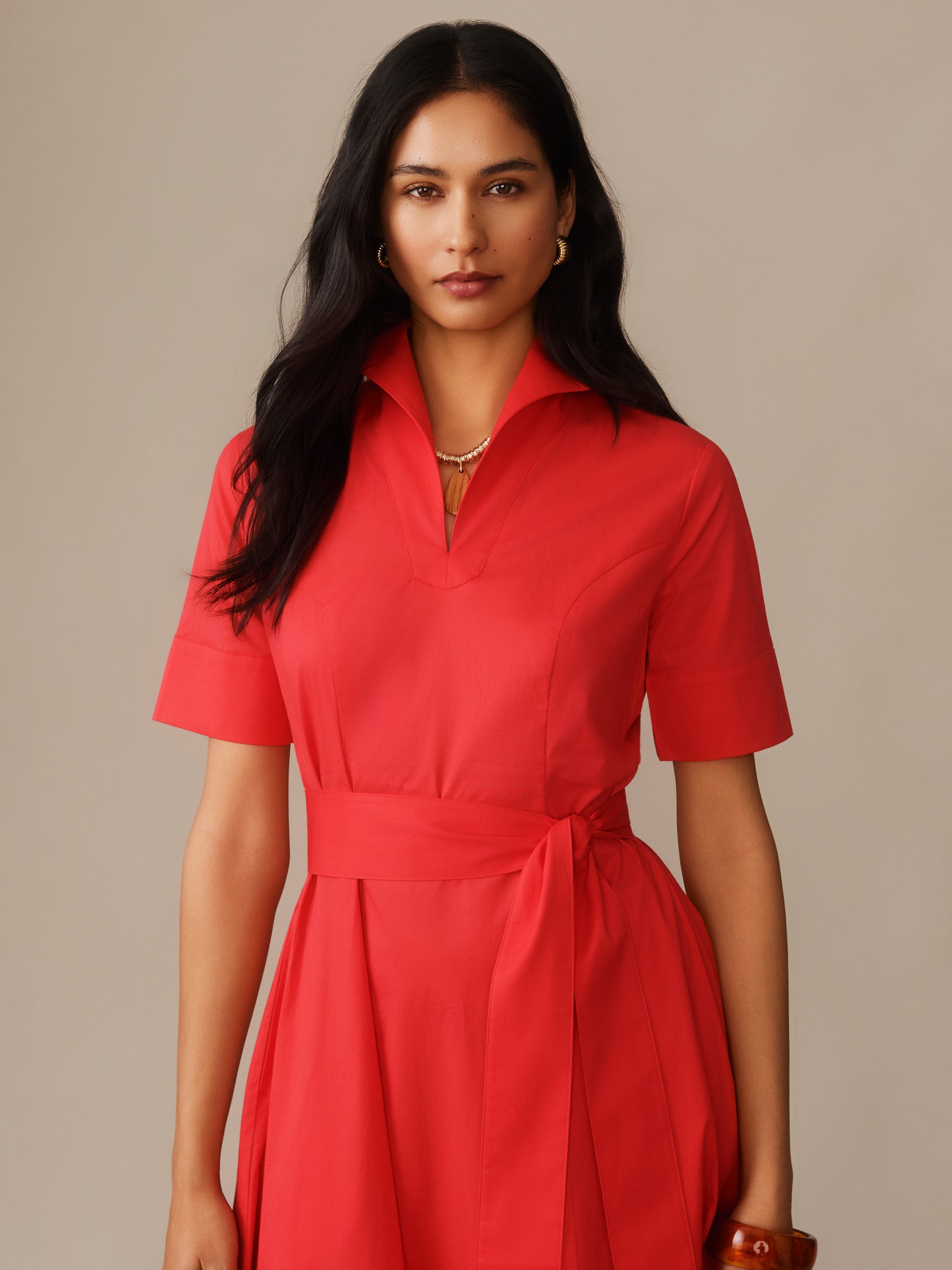 Woman wearing a vibrant red Lily Dress by J.McLaughlin featuring a collared neckline, short sleeves, and a tied waist belt, reflecting effortlessly stylish, enduring designs.