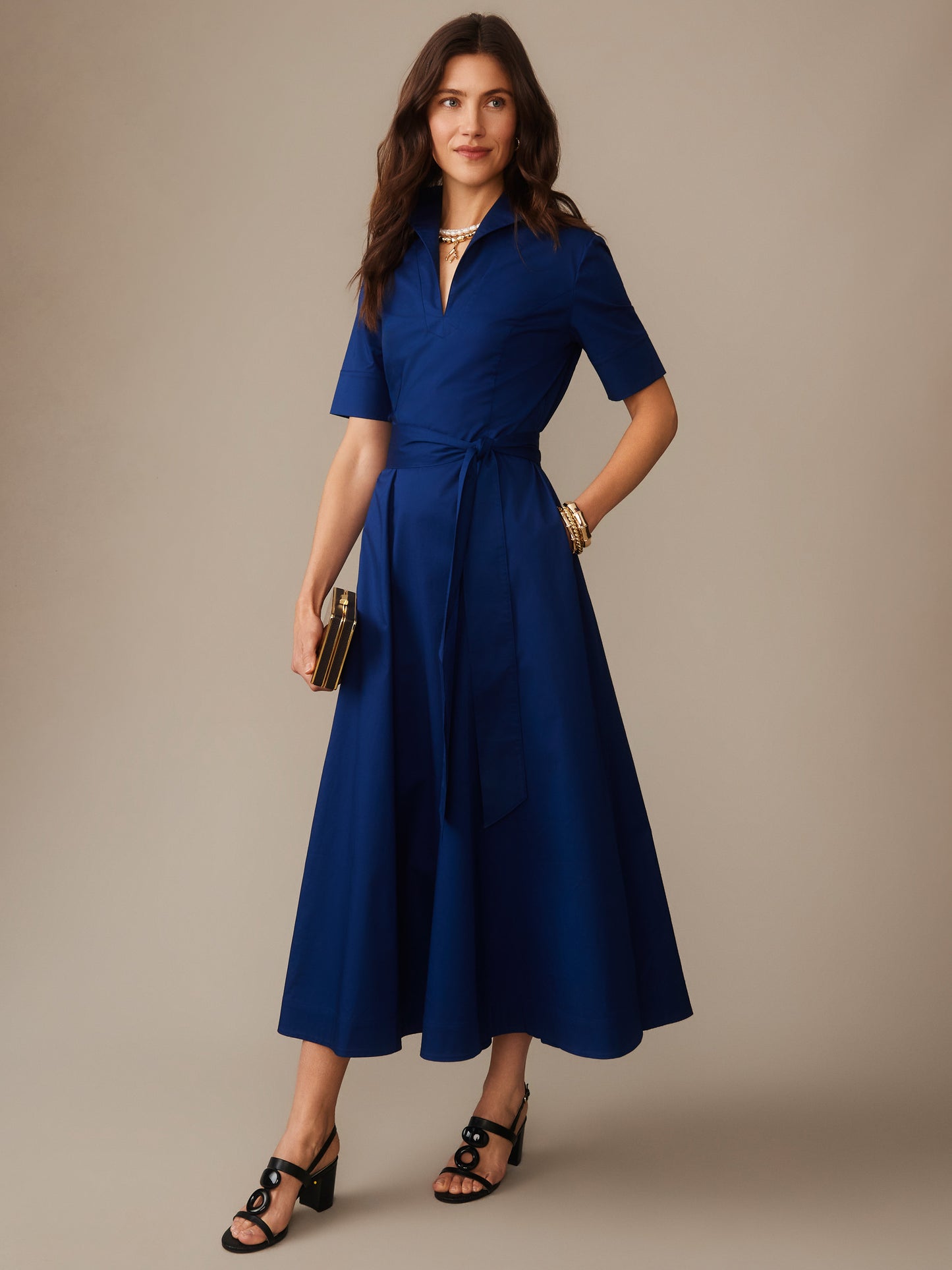 A woman wears the Lily Dress by J.McLaughlin in deep navy blue, featuring a wrap-style waist and short sleeves, perfectly blending effortlessly stylish, enduring designs with innovative fabrics.