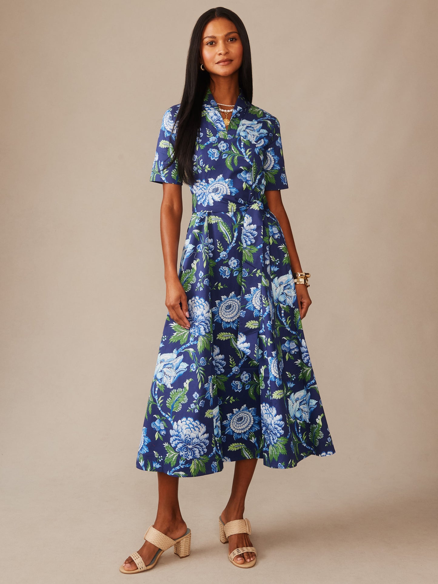 Woman wearing a J.McLaughlin Lily Dress in Cerulean Garden, featuring a floral pattern in blue and green tones, styled with neutral sandals, showcasing effortlessly stylish, enduring designs.