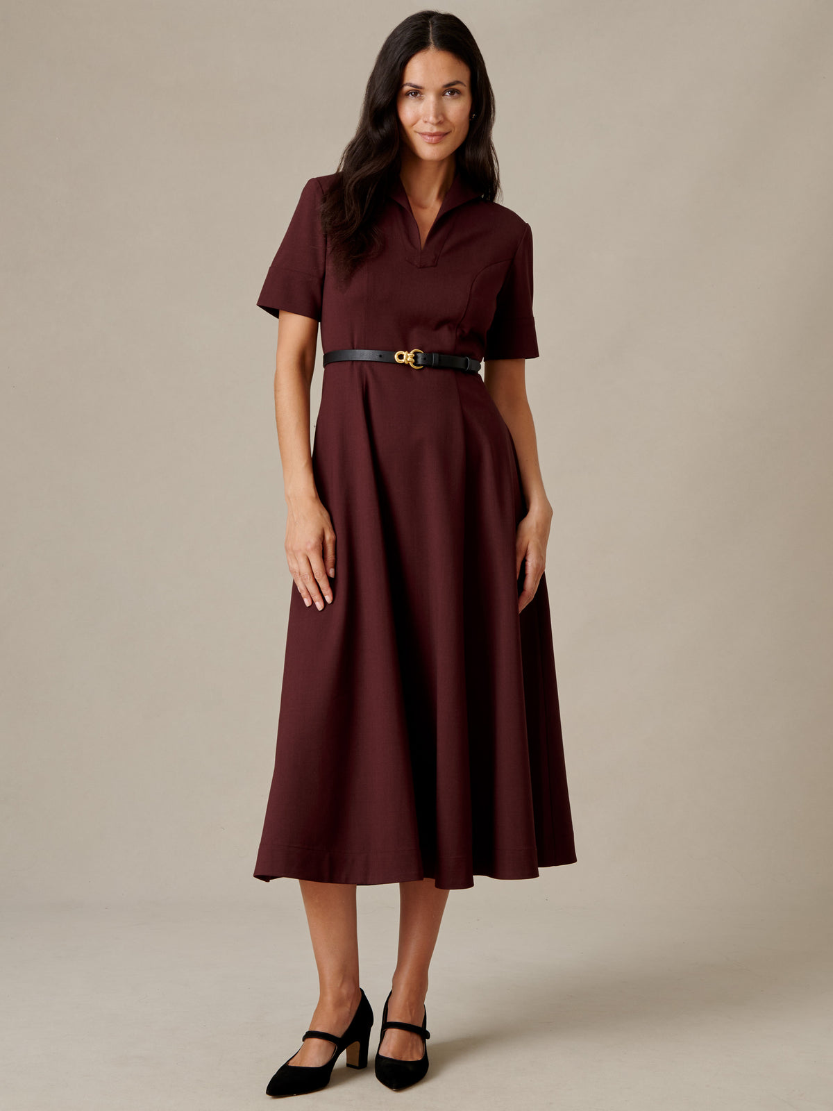 J.McLaughlin Lily Wool Twill Dress in burgundy with a collared V neckline and waist tie styled with black heels on a model