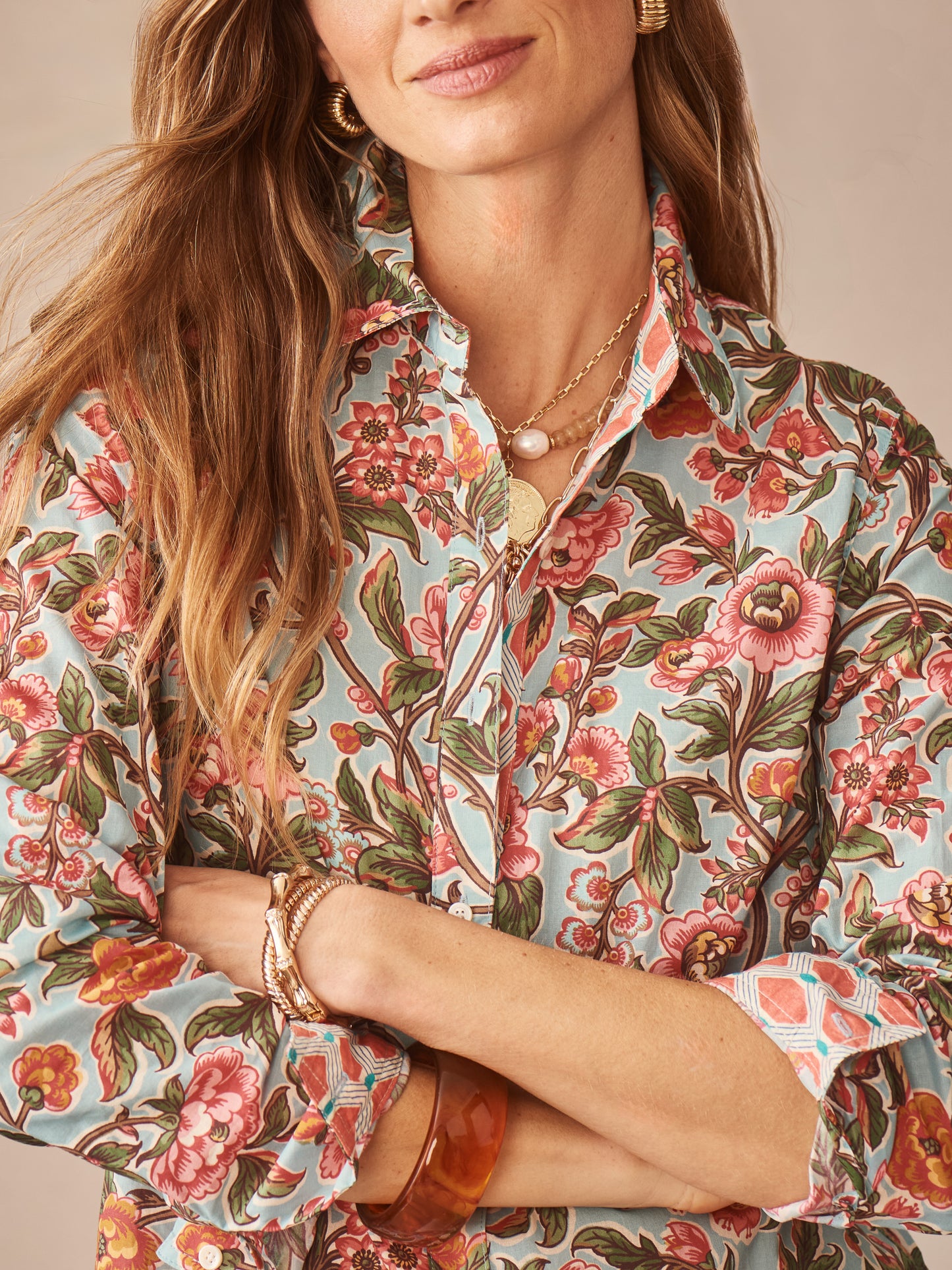 A woman wearing the Lois Shirt in Bucolic Beekeeper by J.McLaughlin, featuring an effortlessly stylish floral print in soft blue and coral tones, embodying enduring designs and a legacy of timeless fashion. A destination for defining style. Life, Well-Lived.