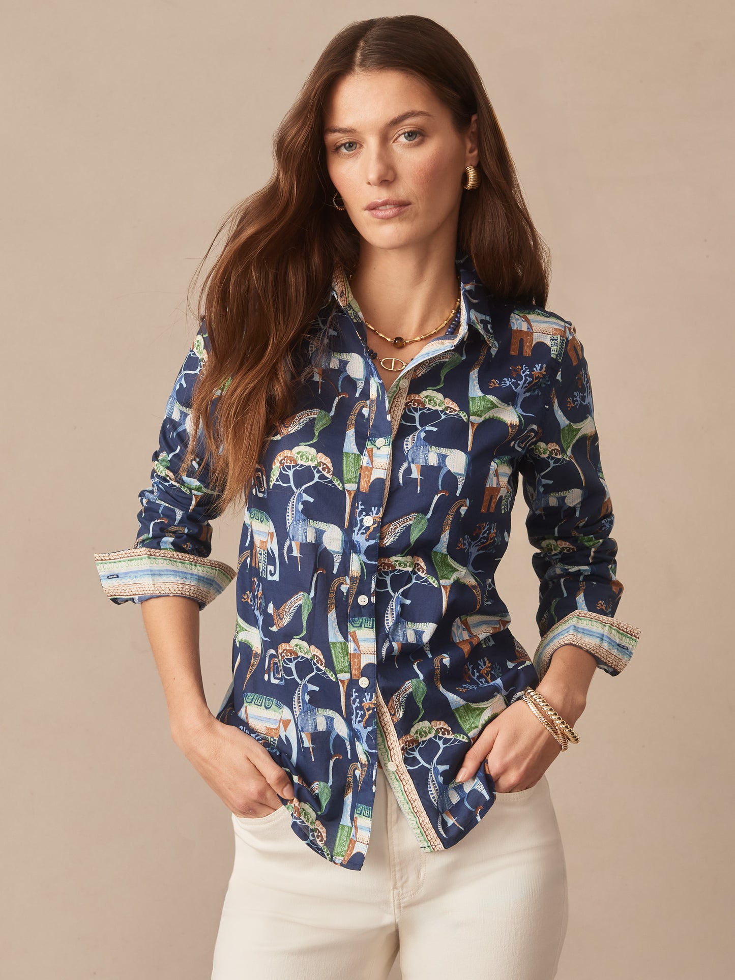 Woman wearing a Lois Shirt in The Wild Stripe by J.McLaughlin, featuring a navy print with animals, styled with rolled sleeves and white pants, embodying effortlessly stylish, enduring designs.