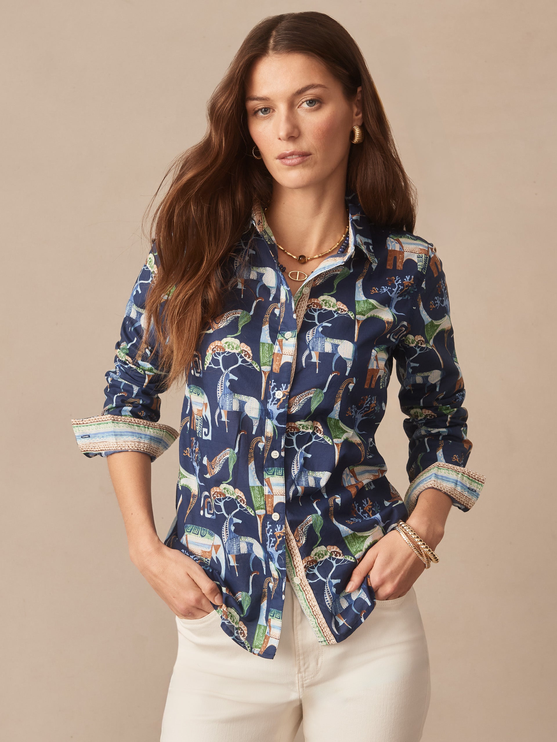 Woman wearing a Lois Shirt in The Wild Stripe by J.McLaughlin, featuring a navy print with animals, styled with rolled sleeves and white pants, embodying effortlessly stylish, enduring designs.