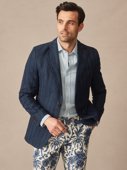 Man wearing a Brera Linen Silk Sport Coat in Stripe by J.McLaughlin, styled with a light blue shirt and patterned pants, showcasing effortlessly stylish, enduring designs with innovative fabrics.