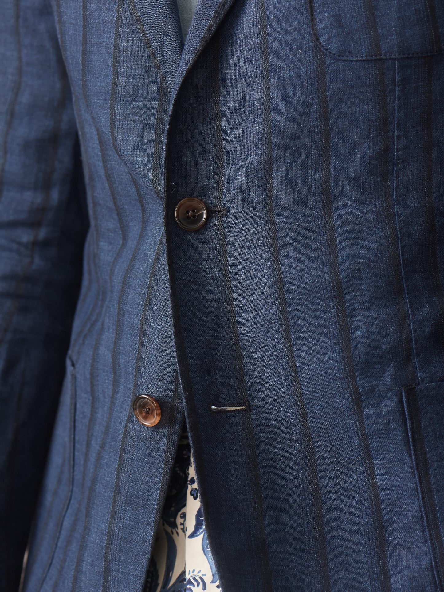 Close-up of a navy striped sport coat made from linen and silk, highlighting the fine craftsmanship of J.McLaughlin’s Brera Linen Silk Sport Coat in Stripe, showcasing effortlessly stylish, enduring designs with innovative fabrics.