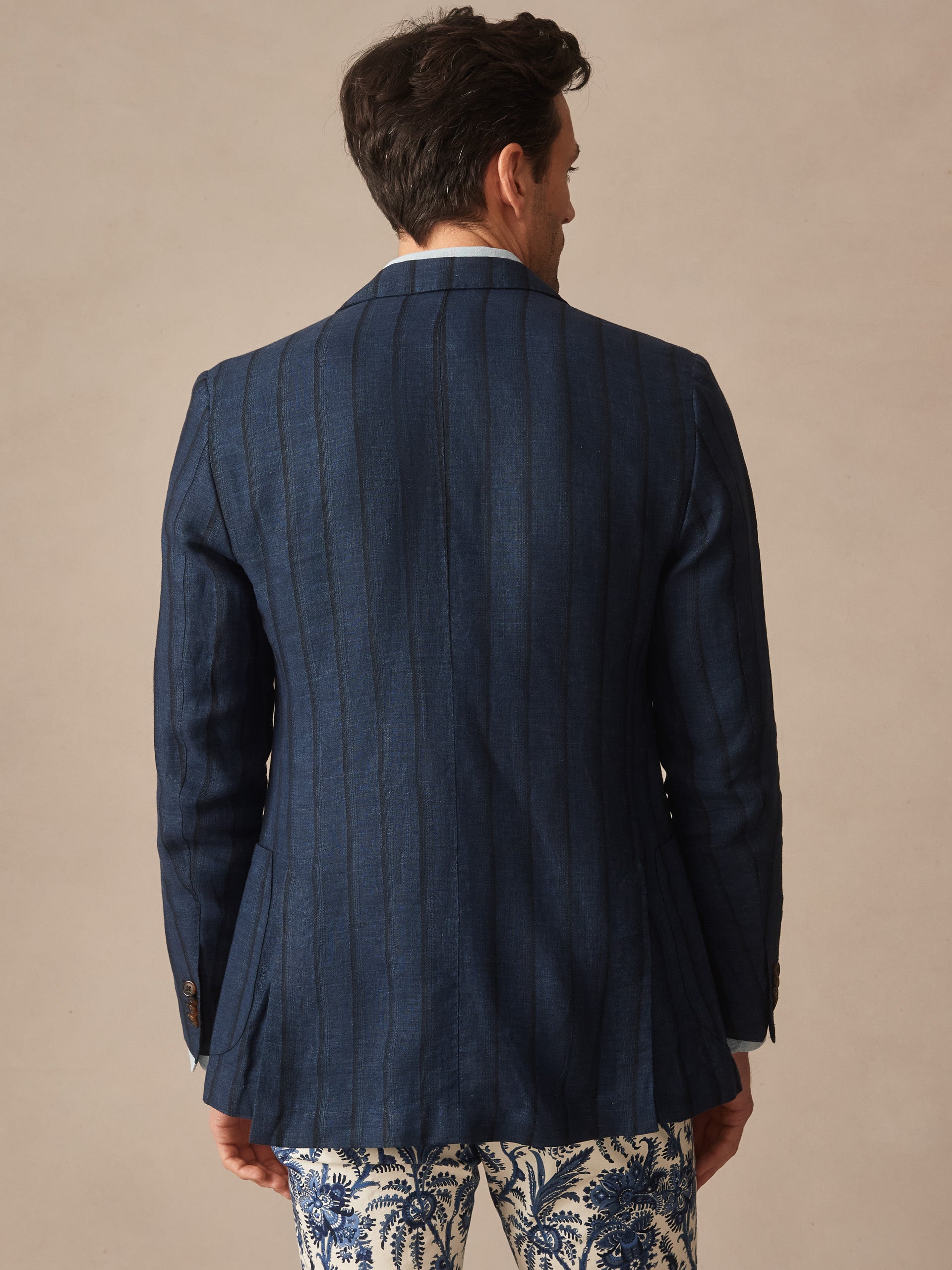 Man seen from behind wearing the Brera Linen Silk Sport Coat in Stripe by J.McLaughlin, paired with patterned pants, showcasing effortlessly stylish craftsmanship and enduring designs in innovative fabrics.
